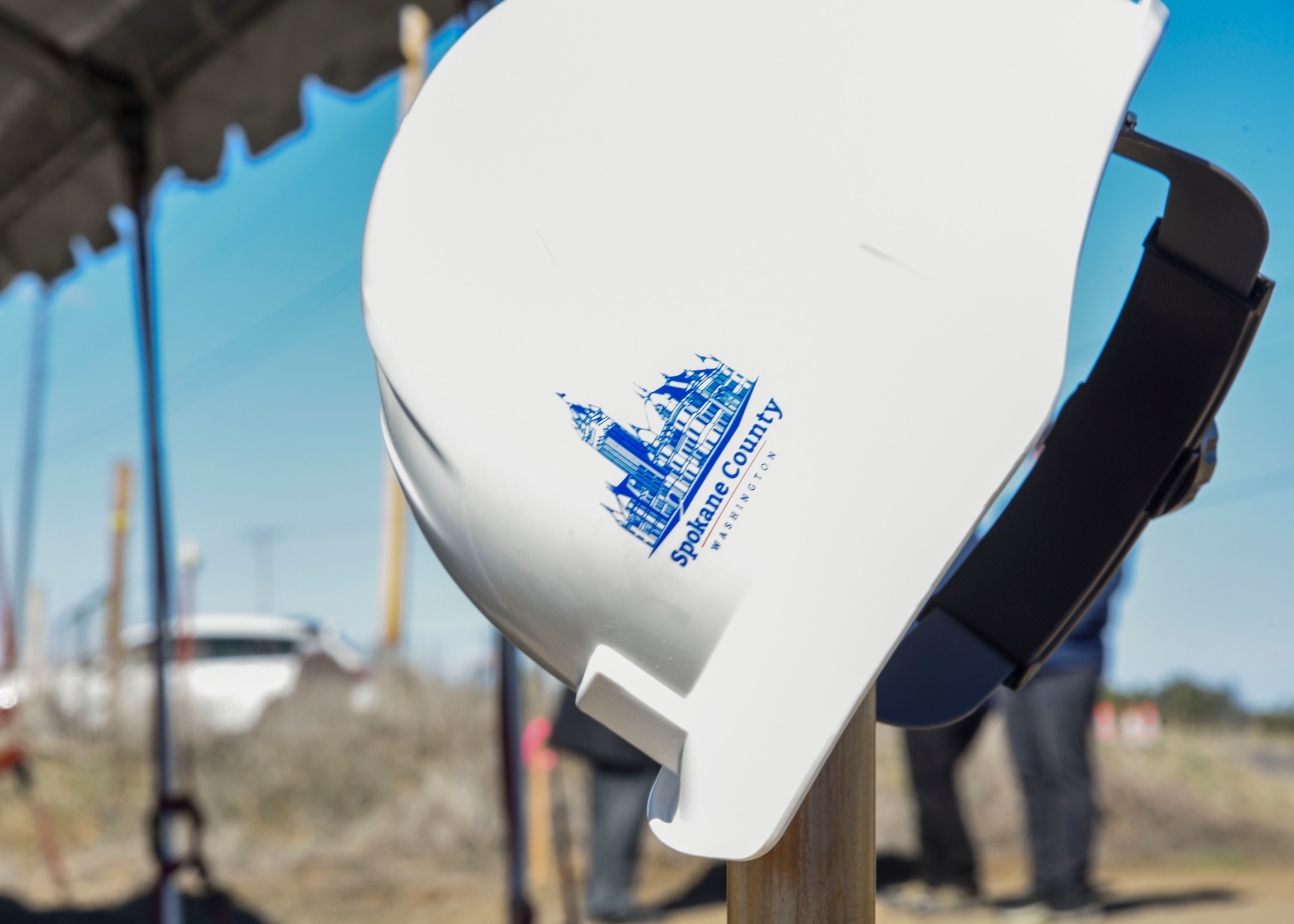 A Spokane County hard hat is displayed on a shovel at a groundbreaking ceremony.
