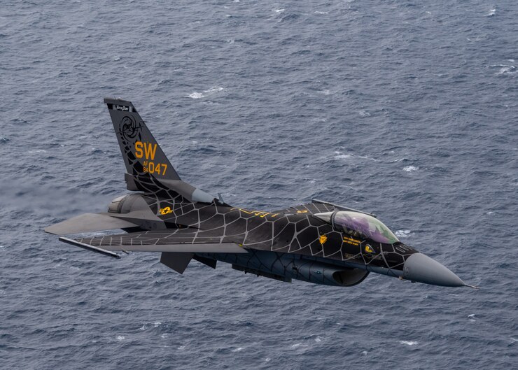 A picture of an F-16 Fighting Falcon flying over the ocean. 