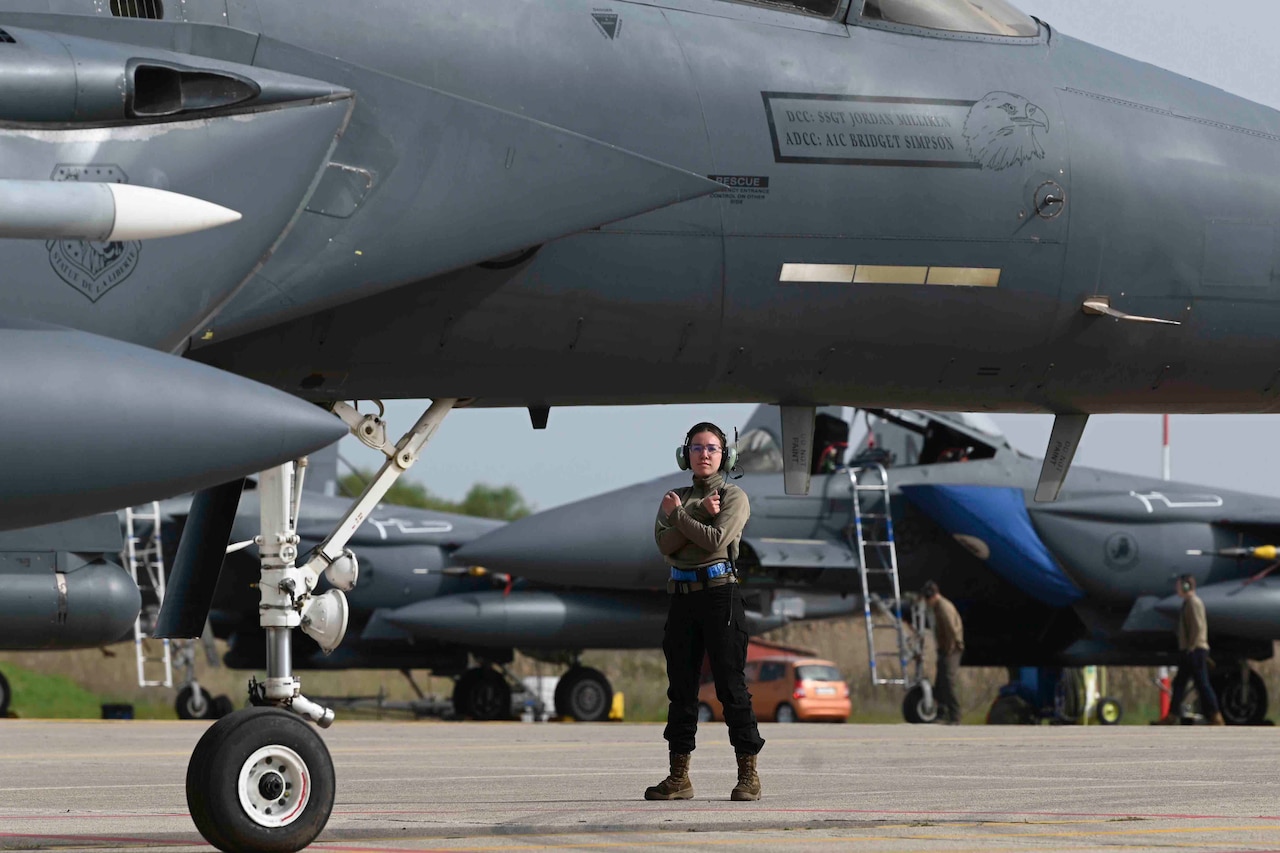 An airman stands near a jet.