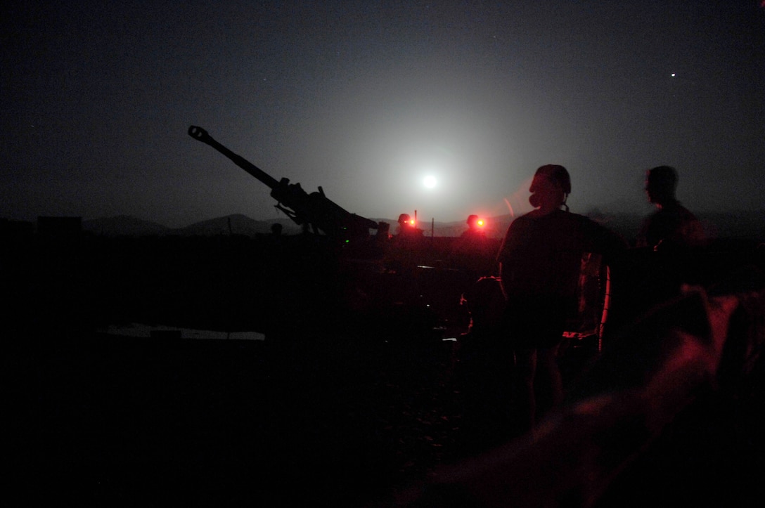 A large gun and soldiers are in silhouette.