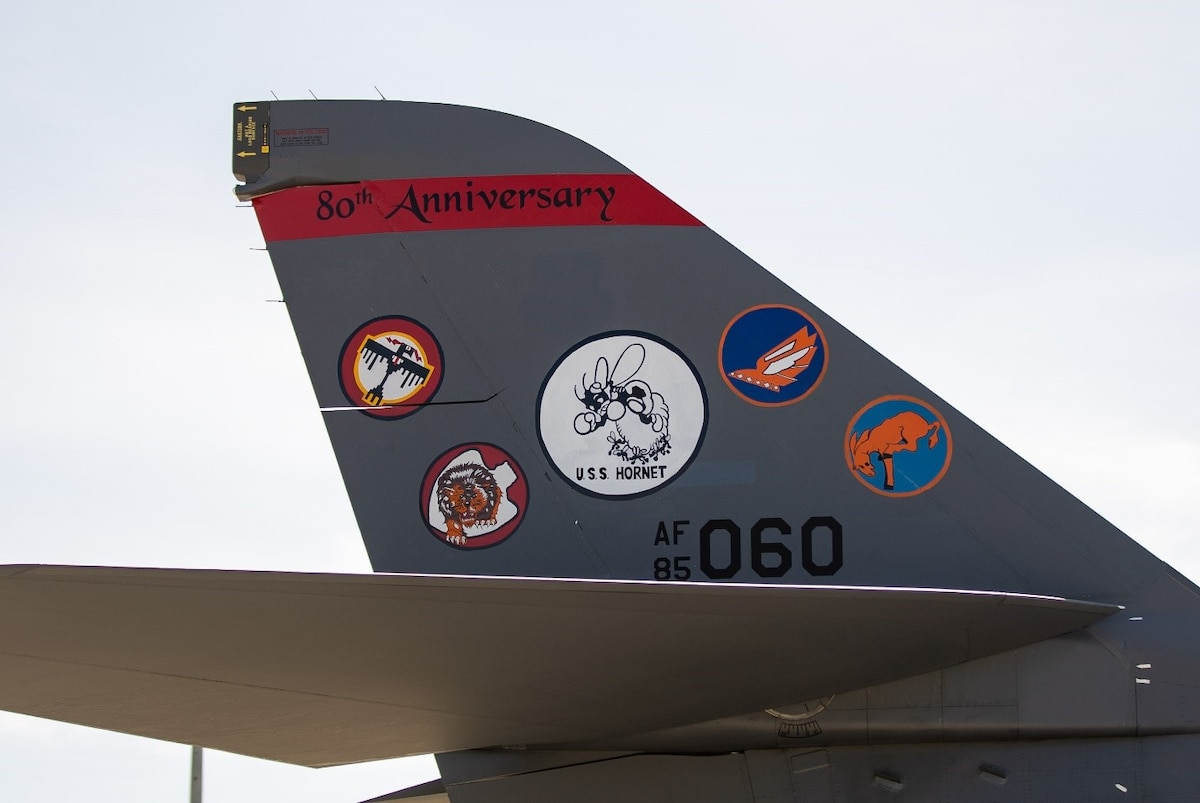 A B-1B Lancer decorated for the 80th anniversary of the Doolittle Raid with the original patches of the four squadrons that participated in the Raid rests on the flightline at Ellsworth Air Force Base, S.D., April 18, 2022. The new tail flash design includes a B-25 Bomber, the Doolittle crest, and five patches from the original Doolittle crews. (U.S. Air Force photo by Senior Airman Austin McIntosh)