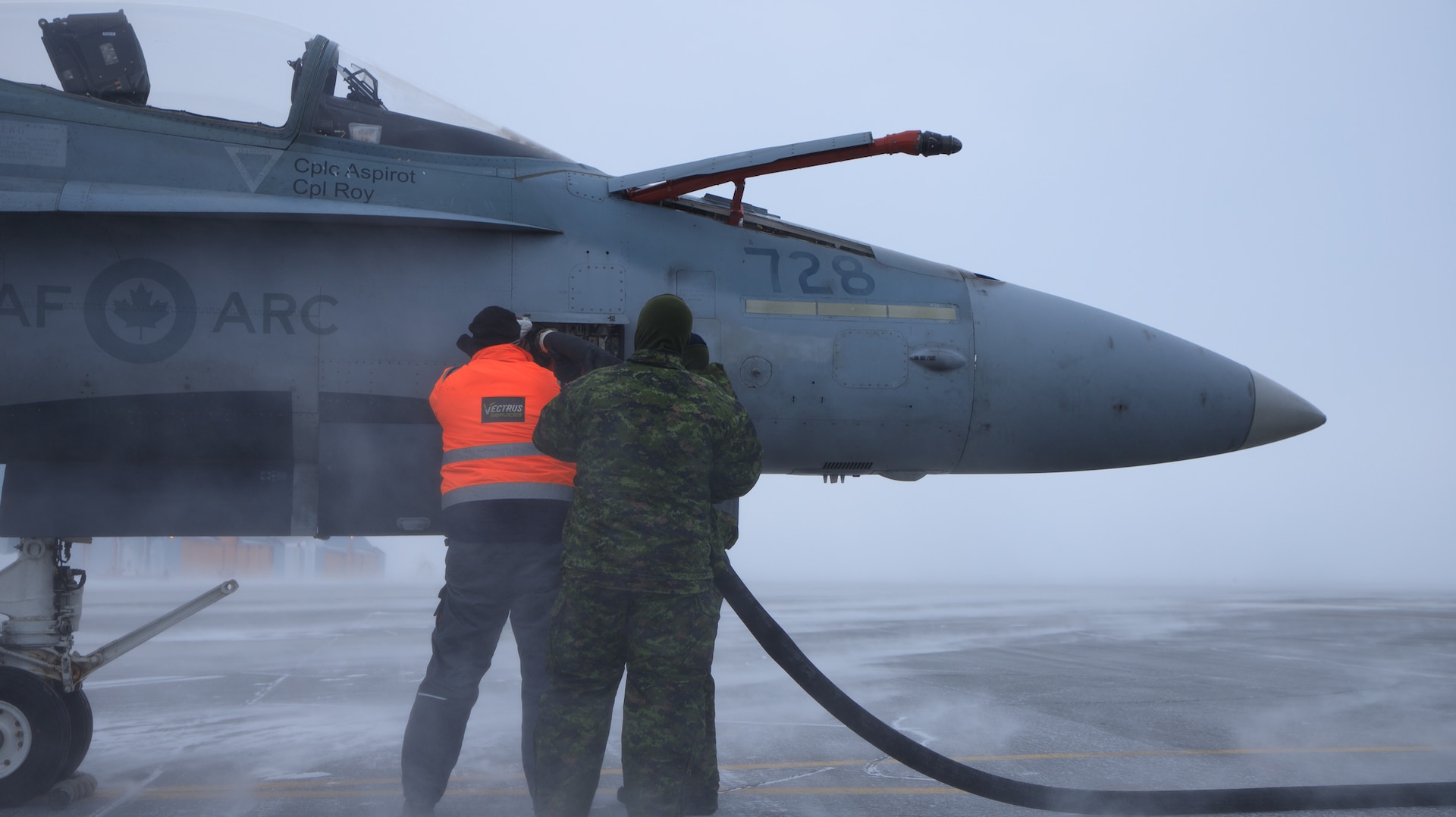 American and Canadian servicemembers refuel a Royal Canadian Air Force CF-18 Hornet at Thule Air Base, Greenland, March 15, 2022, during Operation NOBLE DEFENDER.