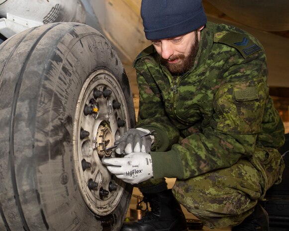 A Royal Canadian Air Force aircraft maintainer conducts pre-flight checks on CF-18 Hornet tires during Operation NOBLE DEFENDER, March 14, 2022.