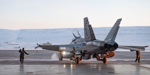 A servicemember guides a Royal Canadian Air Force CF-18 Hornet into the hangar upon arrival at Thule Air Base, Greenland, for Operation NOBLE DEFENDER, March 14, 2022.