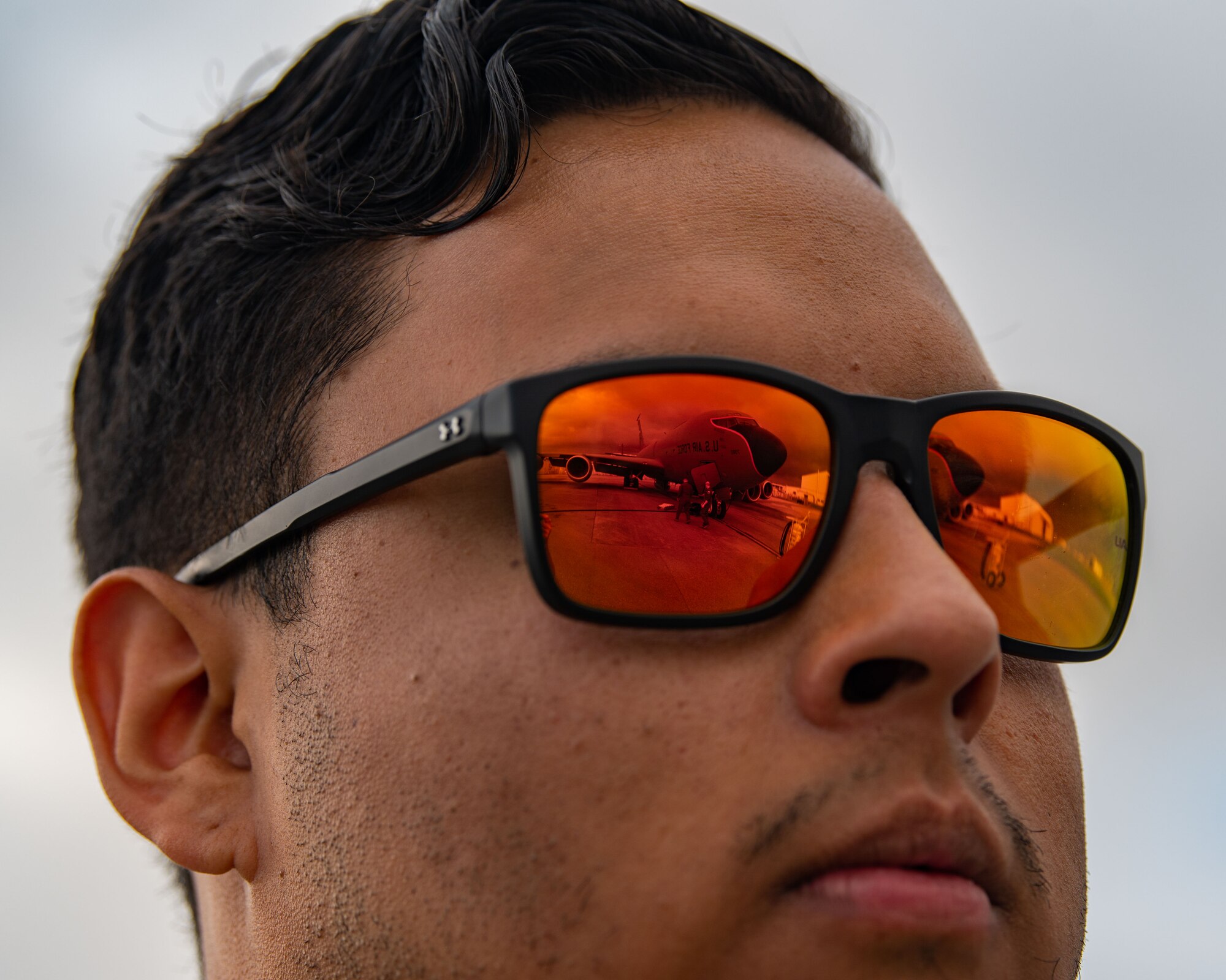 An airman's shades show a reflection of a plane