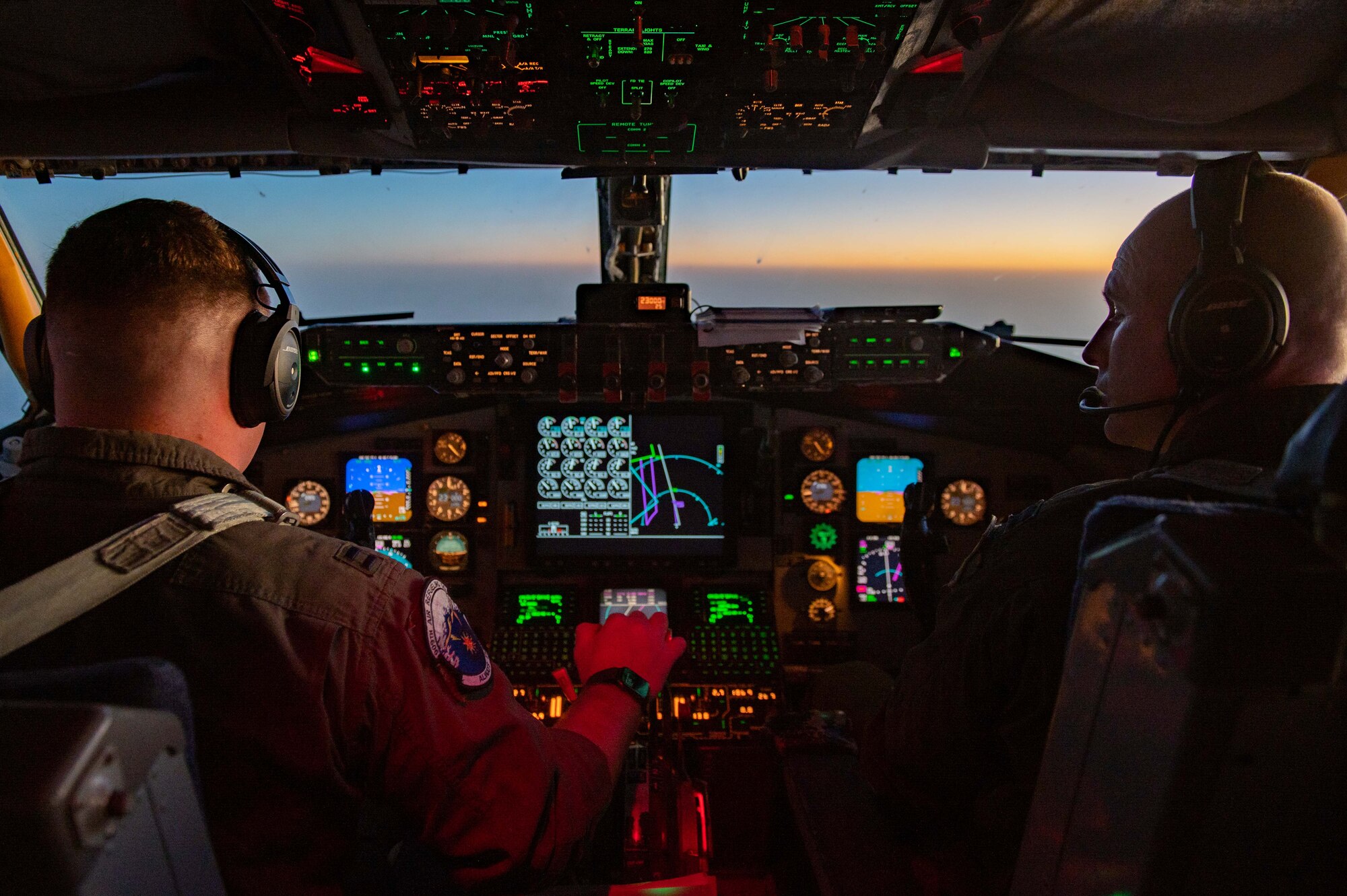 Two pilots steer a plane at sunset
