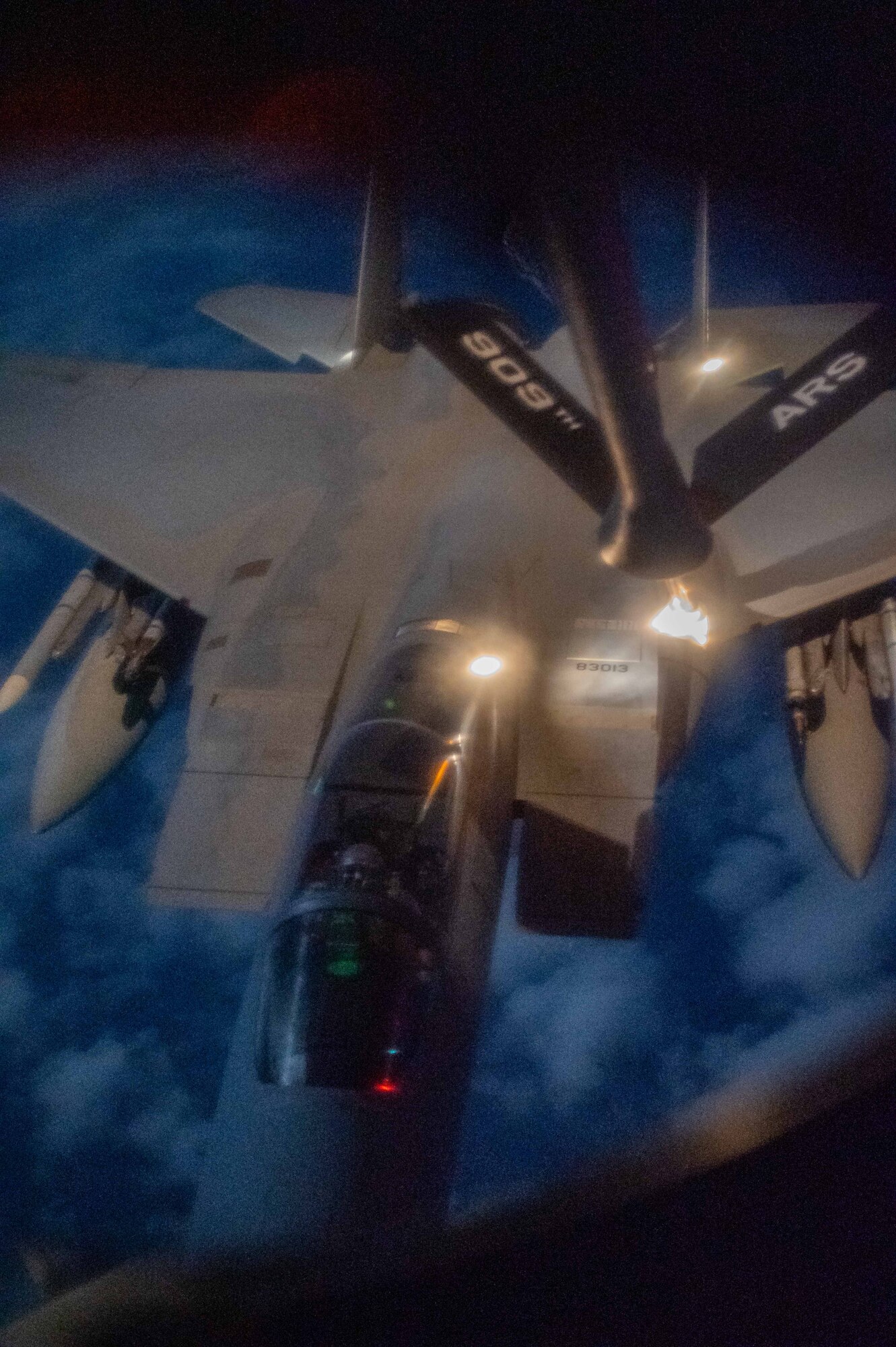 A fighter jet gets refueled by a KC-135 Stratotanker at night