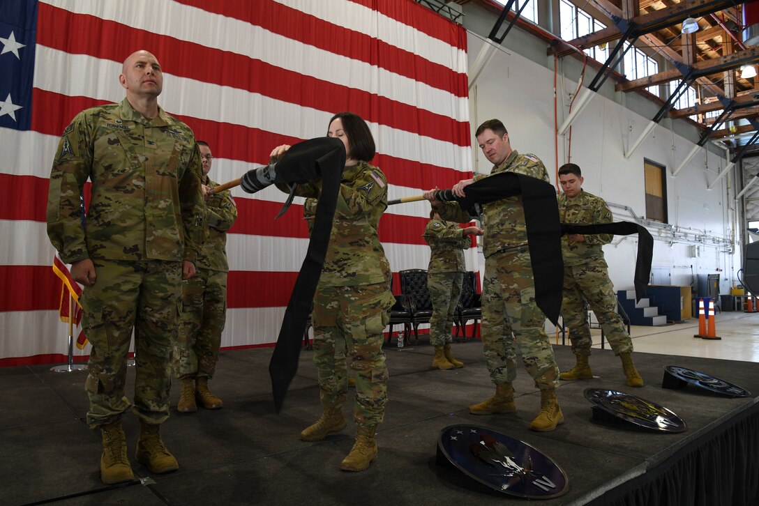 PETERSON SPACE FORCE BASE, Colo. – U.S. Space Force Lt. Col. Kara Sartori, 4th Space Control Squadron commander, second from left, U.S. Space Force Lt. Col. Alexander Courtney, 5th Space Control Squadron commander, second from right, U.S. Space Force Maj. Kevin Aneshansley, 16th Space Control Squadron director of operations, right, encase the old squadron flags for the 4th, 5th and 16th SPCS during their re-designation ceremony at Peterson Space Force Base, Colorado, April 15, 2022. It is a military custom to furl and encase the flag of an organization when its unit’s mission has been completed.  This serves as a final symbol of closure for all those, past and present, who have served in the organization. (U.S. Space Force photo by Airman 1st Class Aaron Edwards)