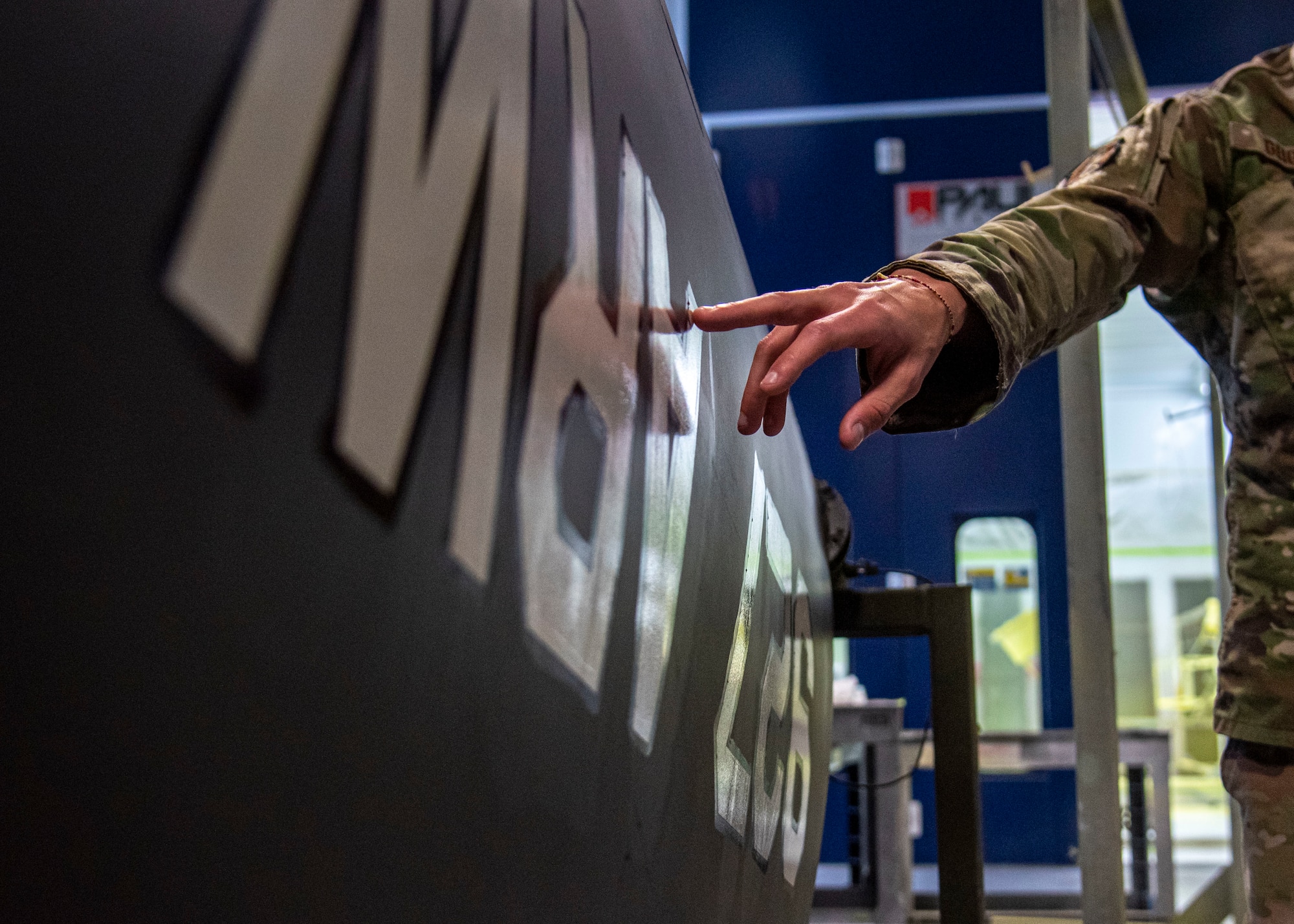 U.S. Air Force Tech. Sgt. Kurtis Geiger, noncommissioned officer in charge of the 6th Maintenance Squadron corrosion control unit, points to a vinyl decal in the corrosion control facility at MacDill Air Force Base, Florida, April 12, 2022.