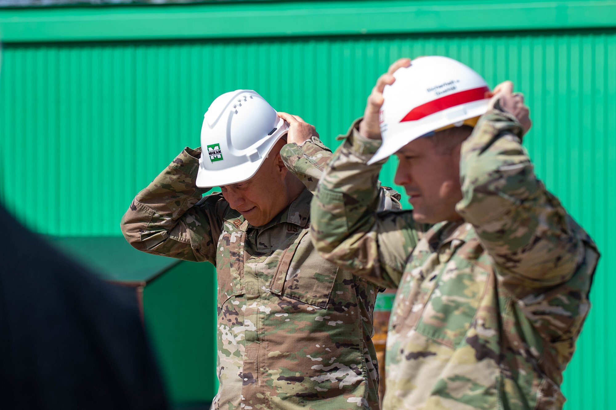 Service members put on hard hats at a construction site