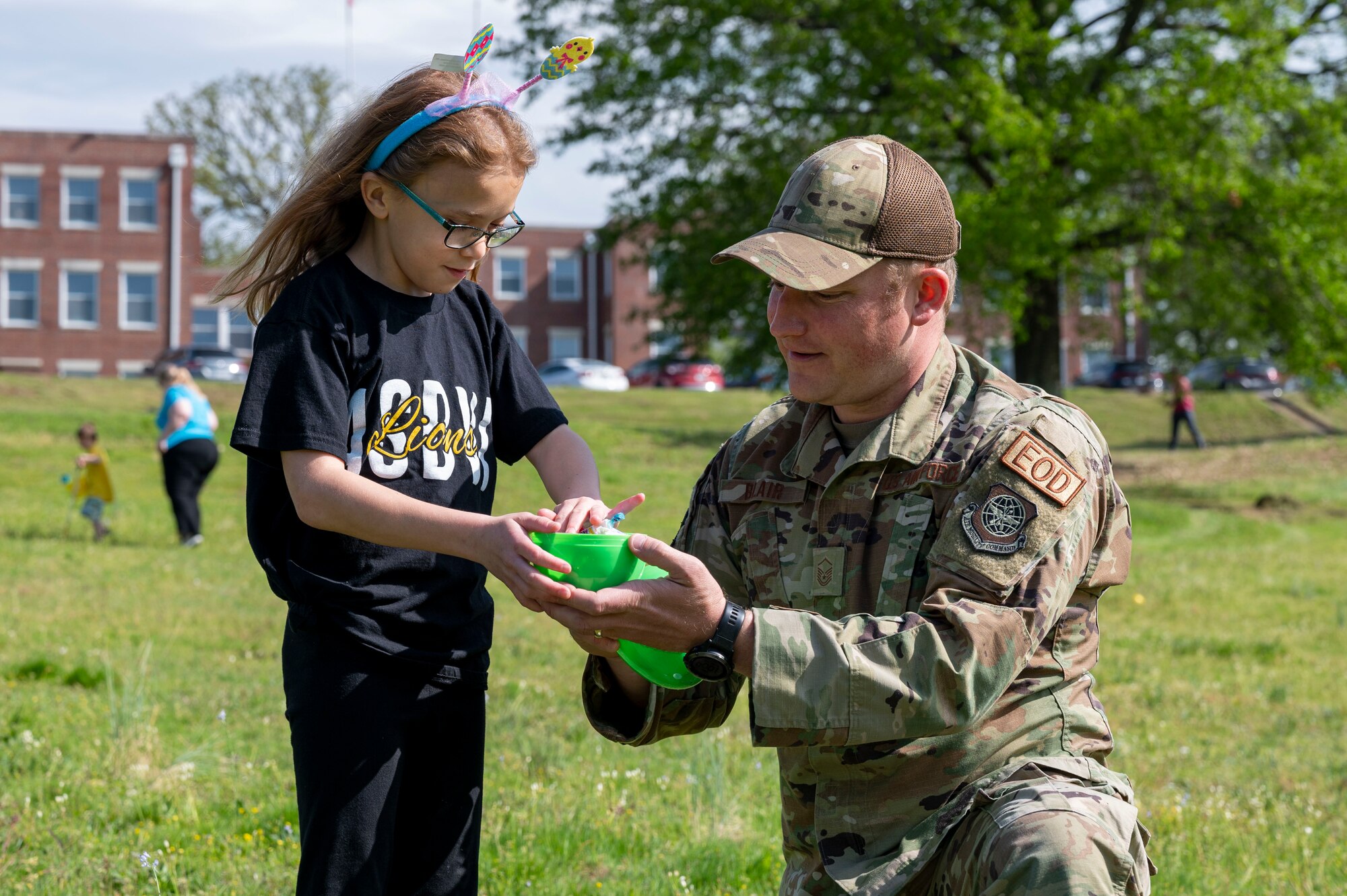 Master Sgt. Alex Blair, 19th Civil Engineer Squadron explosive ordnance exposal technician, shows a student the contents of an Easter egg during an egg hunt