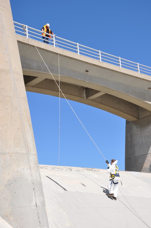 An engineer safely ropes from the crest of Sepulveda Dam into the Los Angeles River, March 22, 2022, in Van Nuys, California