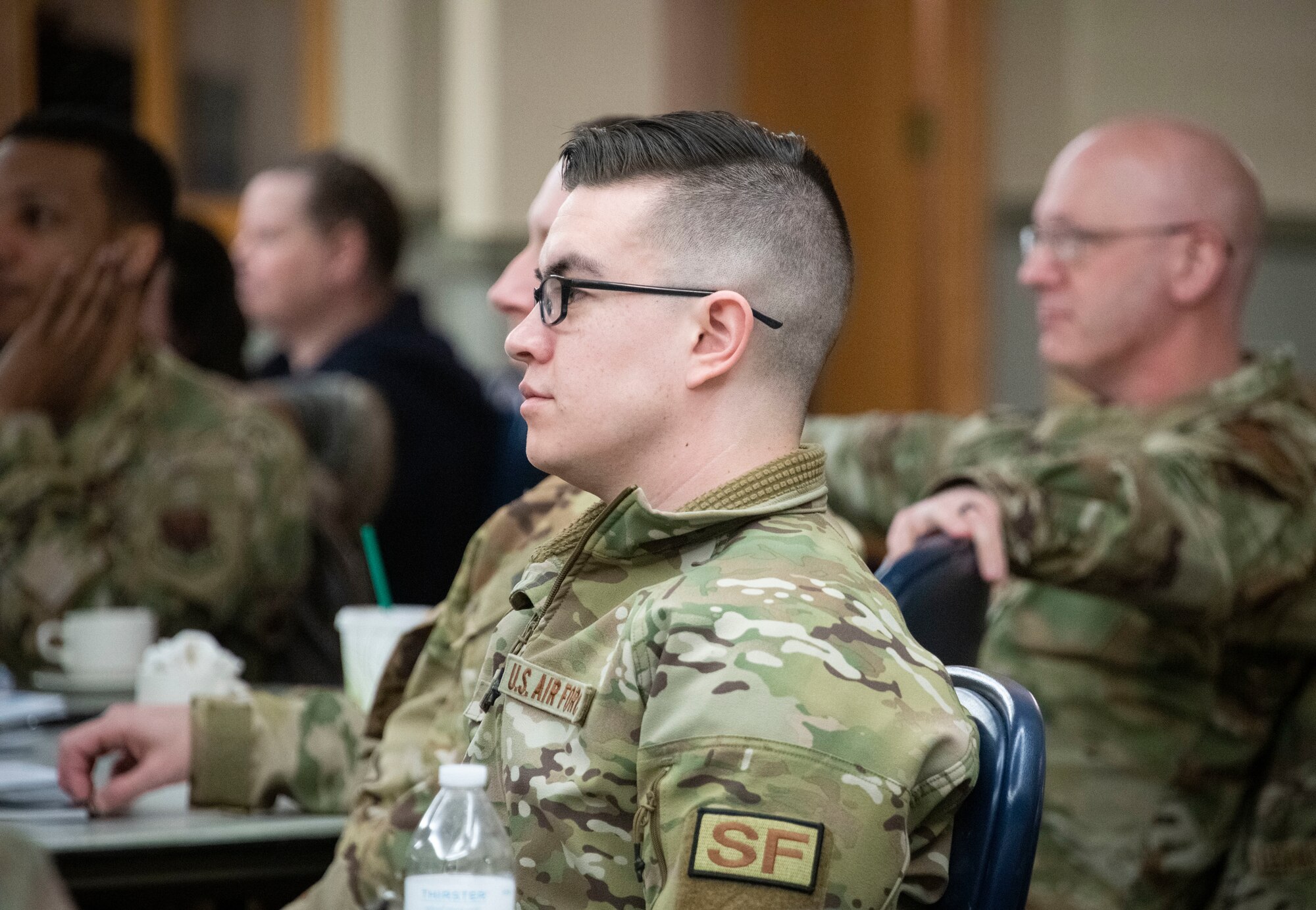 Several Airmen face forward and watch intently as they are briefed.