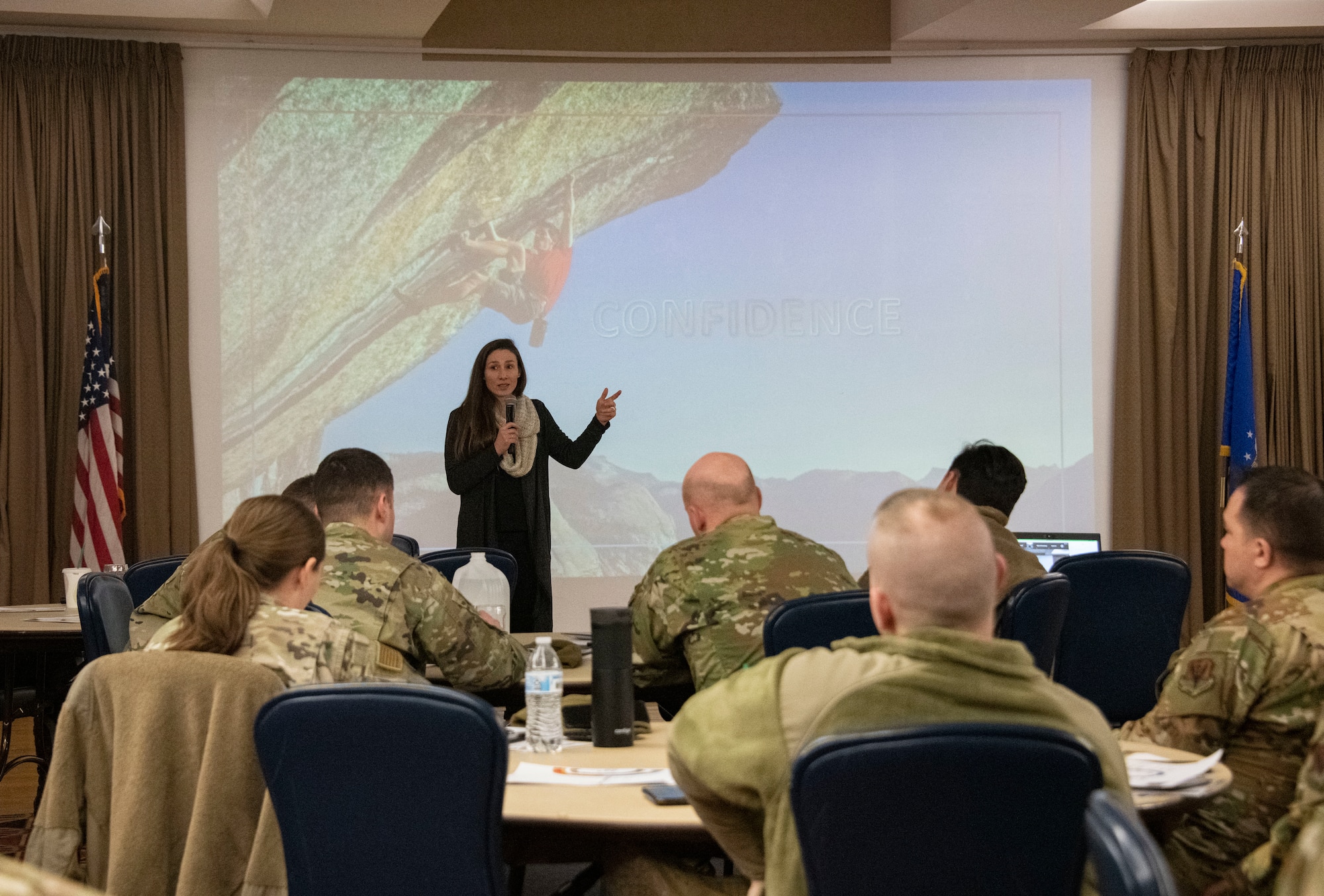 A woman speaks in front of a large crowd of Airmen