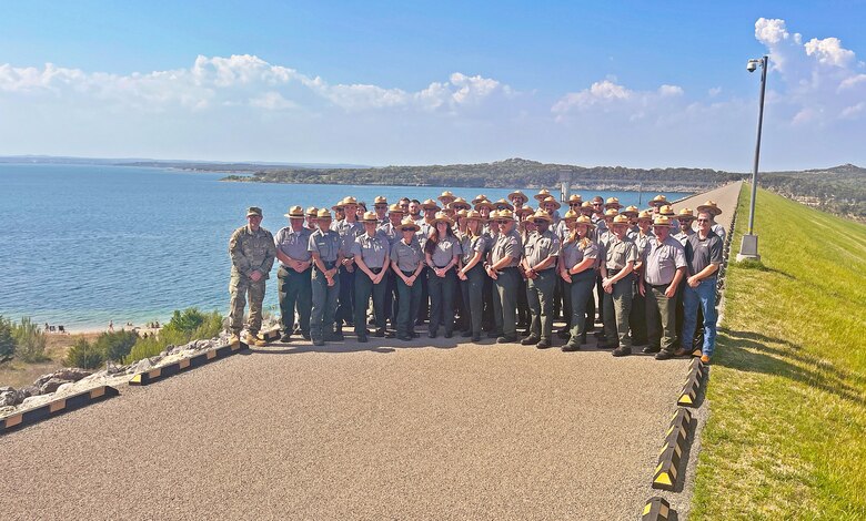 Park rangers pose for a photo on top of a dam