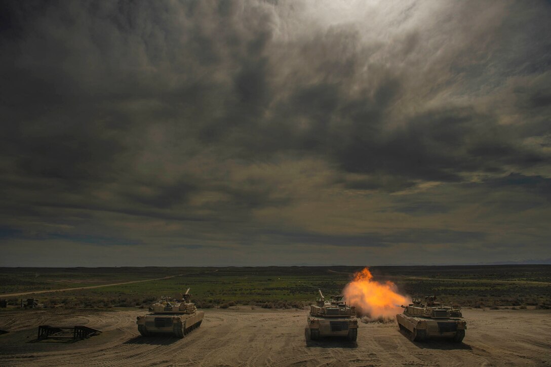 Three tanks parked in a row as one fires.