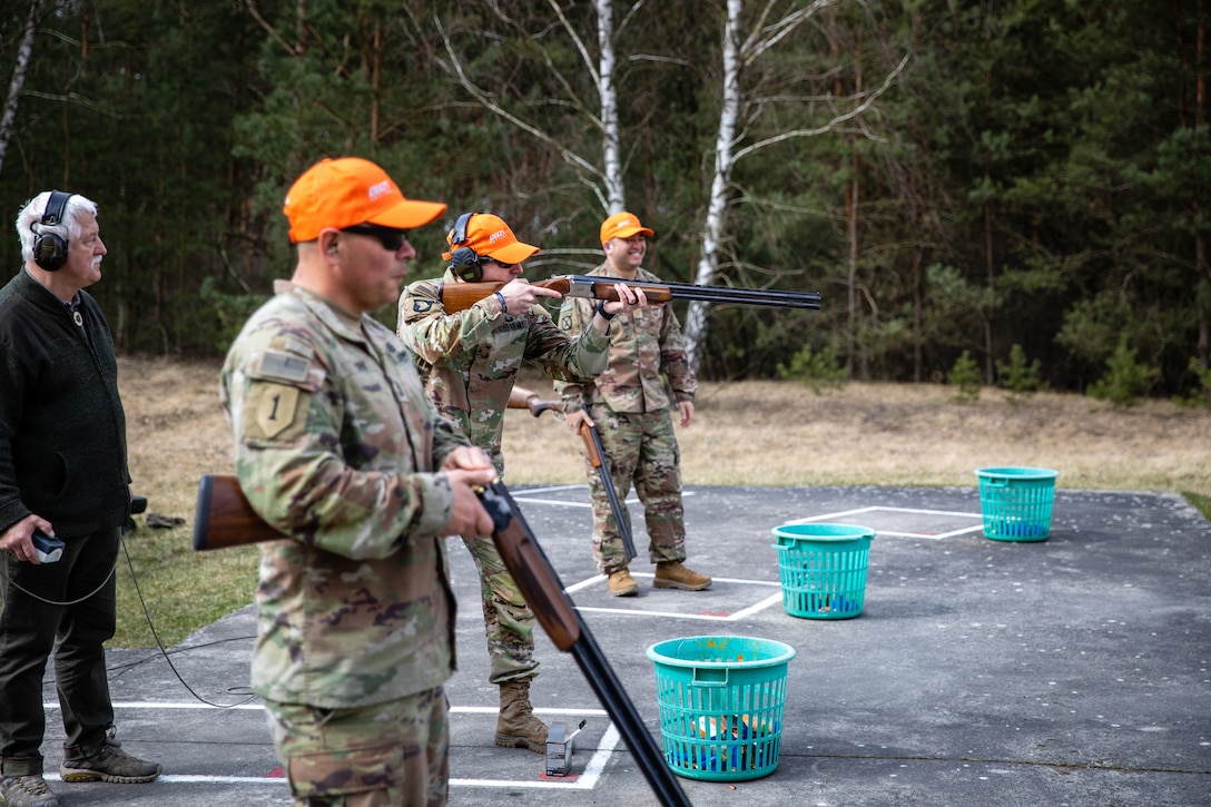 A soldier shoots at a range while other soldiers wait their turn.