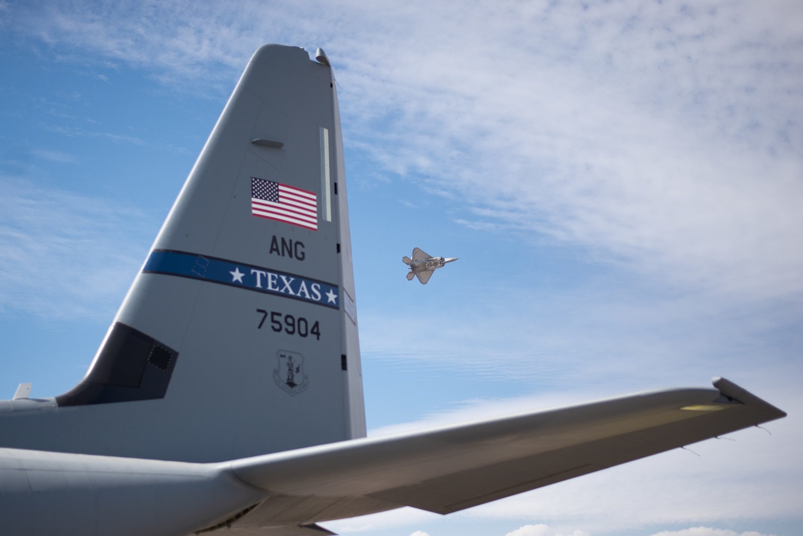 F-22 flies by a C-130J tail.