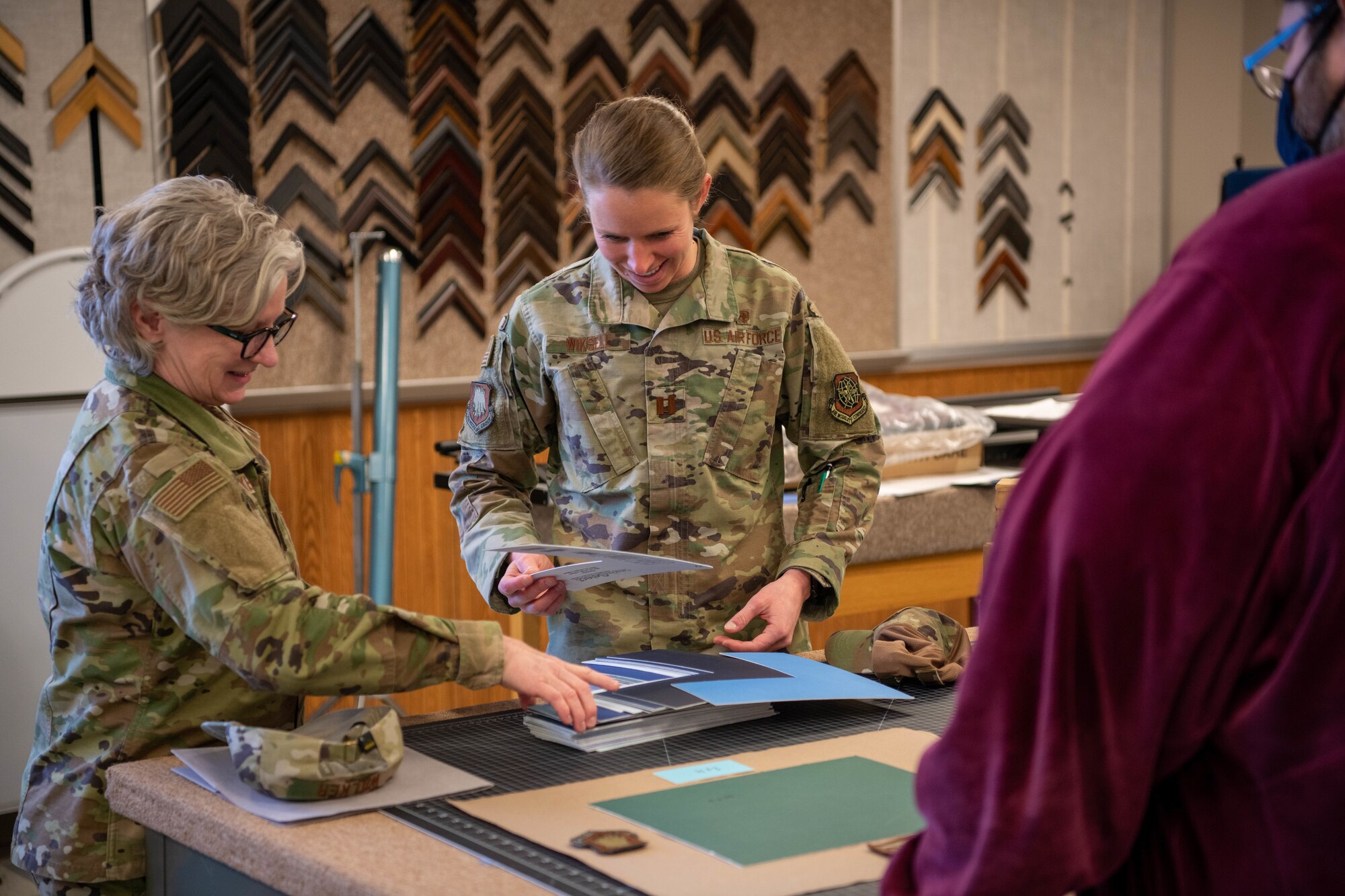 Lieutenant Col. Daniel Walker, 22nd Force Support Squadron director of operations for the Airman Family Readiness Center, and Capt. Anderson Wiksell, 22nd Medical Group practice mananger, explore color options for frame inserts at the Arts and Crafts Center April 14, 2022, at McConnell Air Force Base, Kansas.