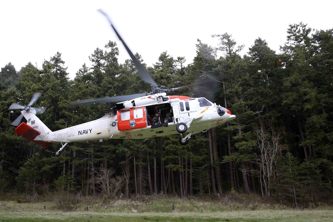 An MH-60 Seahawk helicopter assigned to Naval Air Station Whidbey Island's (NASWI) Search and Rescue (SAR) unit takes off from a training area near NASWI. The SAR team provides assistance to military and civilians throughout the Pacific Northwest.