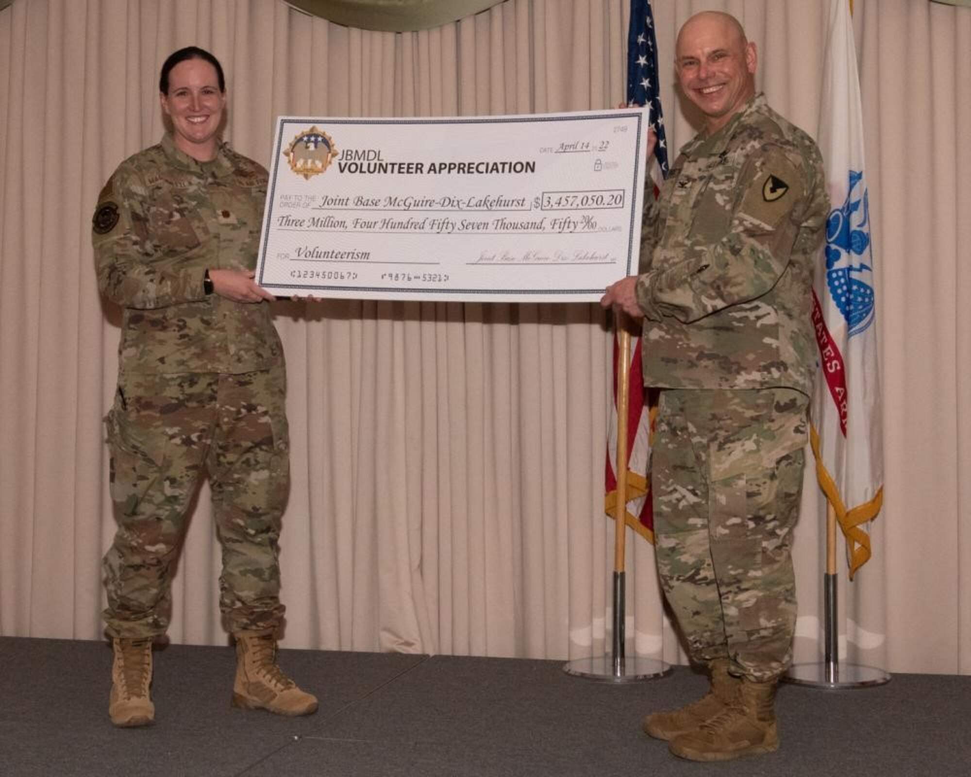 U.S. Air Force Maj. Sarah Marianetti, 87th Force Support Squadron Operations Officer, presents a check to U.S. Army Col. Jon Brierton, Army Support Activity, Fort Dix Commander and Joint Base McGuire-Dix-Lakehurst, N.J., Deputy Commander, April 14, 2022 at Tommy B's Community Activities Center. The check displays the monetary value that Joint Base MDL volunteers offer to the installation and community.