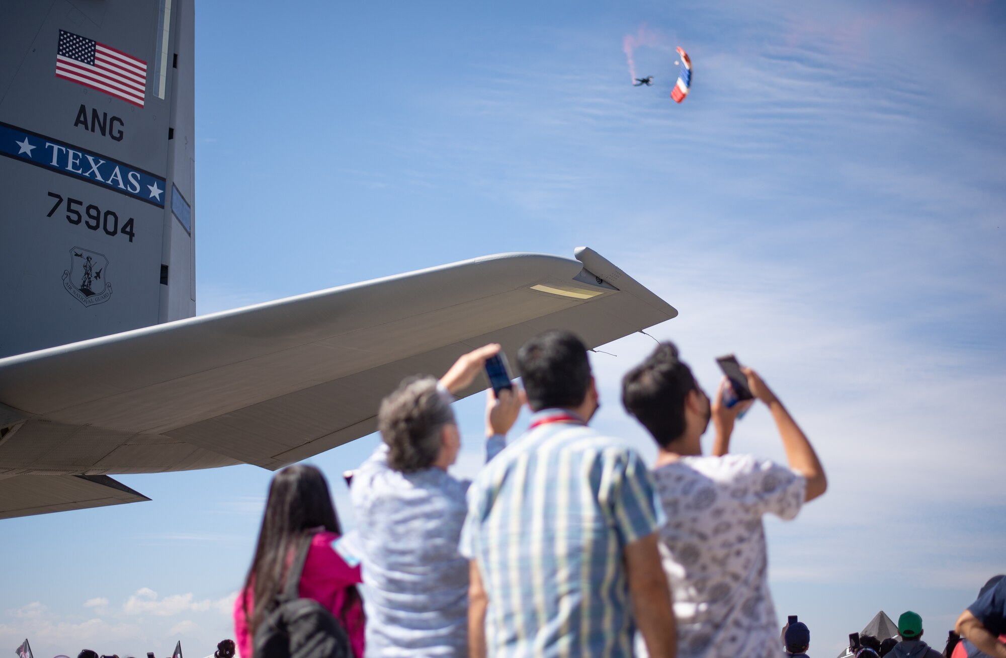 Air Show spectators watch a parachute land.