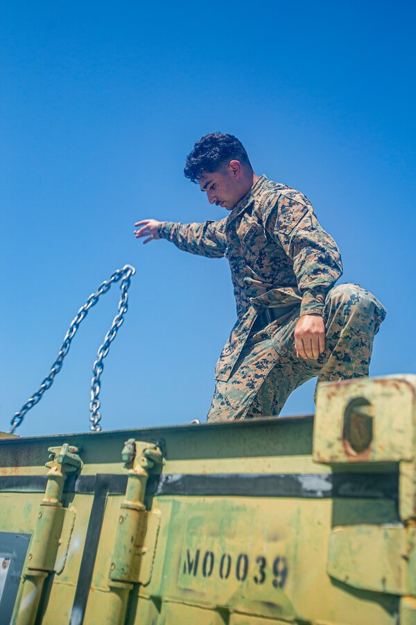 U.S. Marine Corps Lance Cpl. Billy Molina, a landing support specialist with 3rd Landing Support Battalion, 3rd Marine Logistics Group, detaches a chain from a container at Kin Blue, Okinawa, Japan, April 12, 2022. HMH-466 and 3rd Landing Support Battalion, 3rd Marine Logistics Group, conducted ship-to-shore movements to offload gear in support of redeployment from Balikatan 22, an annual joint force exercise in the Republic of the Philippines. (U.S. Marine Corps photo by Cpl. Alex Fairchild)