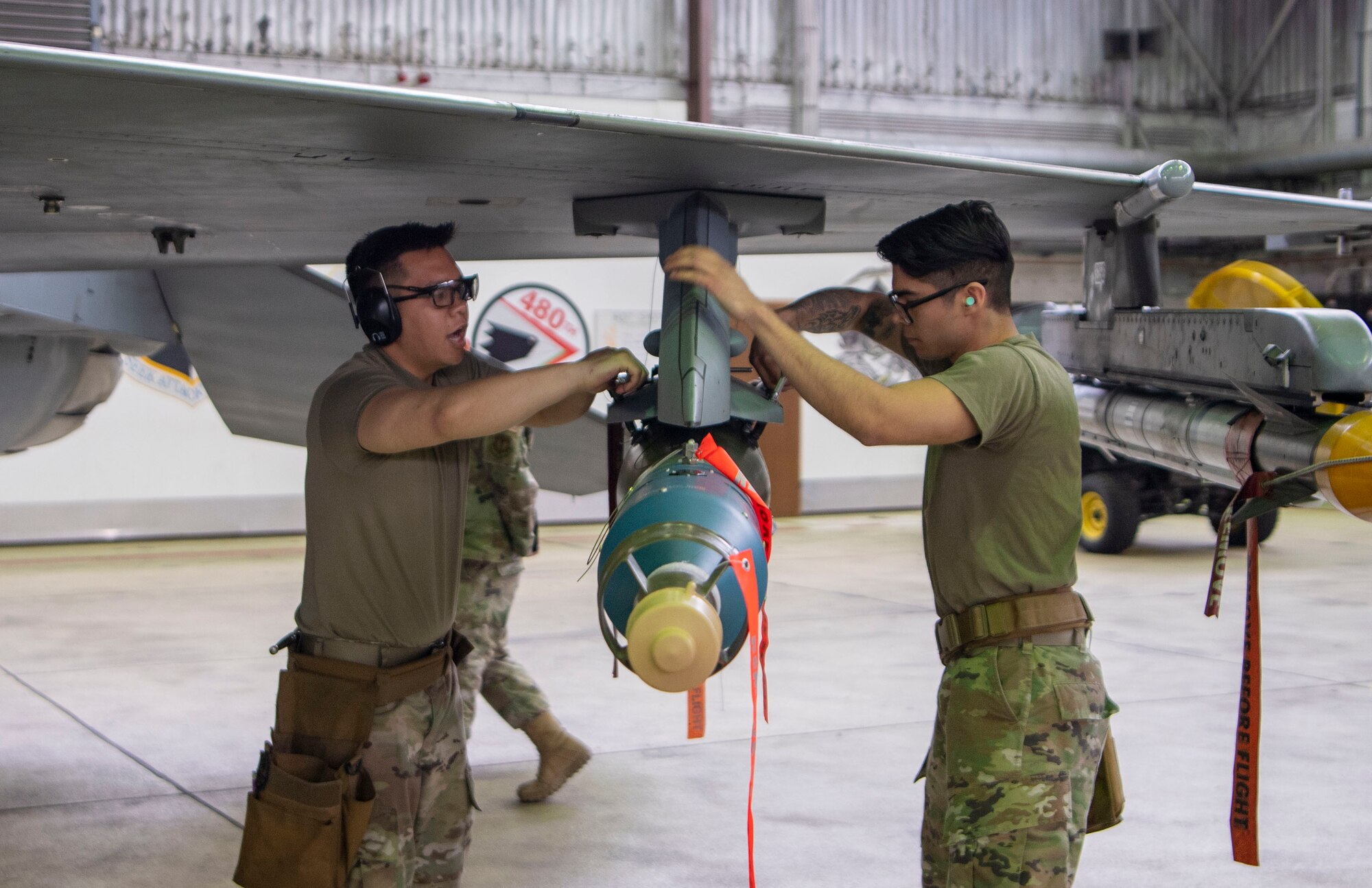 Airman 1st Class Matthew Taitingfong, 480th Fighter Squadron weapons crew member, and Staff Sgt. Kevin Gonzalez-Barba, 480th FS weapons crew team chief, secure a GBU-12 paramount onto an F-16 Fighting Falcon fighter aircraft during the Weapons Load Crew of the Quarter competition at Spangdahlem Air Base, Germany, April 14, 2022. Unfortunately, Saber Nation fell short of the win in the first competition against an F-35A Lightning II fifth-generation aircraft weapons load crew. (U.S. Air Force photo by Airman 1st Class Jessica Sanchez-Chen)