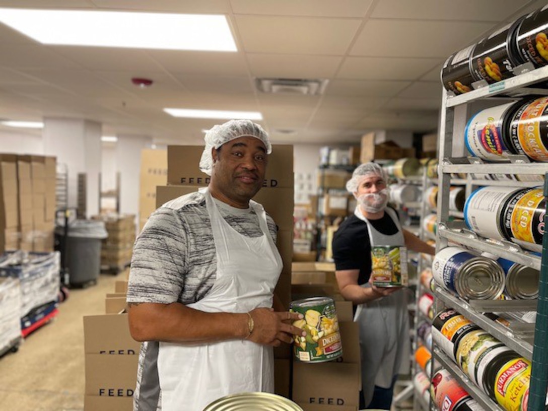DLA Aviation Logistics Operations Center team members;  Eddy Murillo and Josh Stanley, sort cans of food during a volunteer team building event.