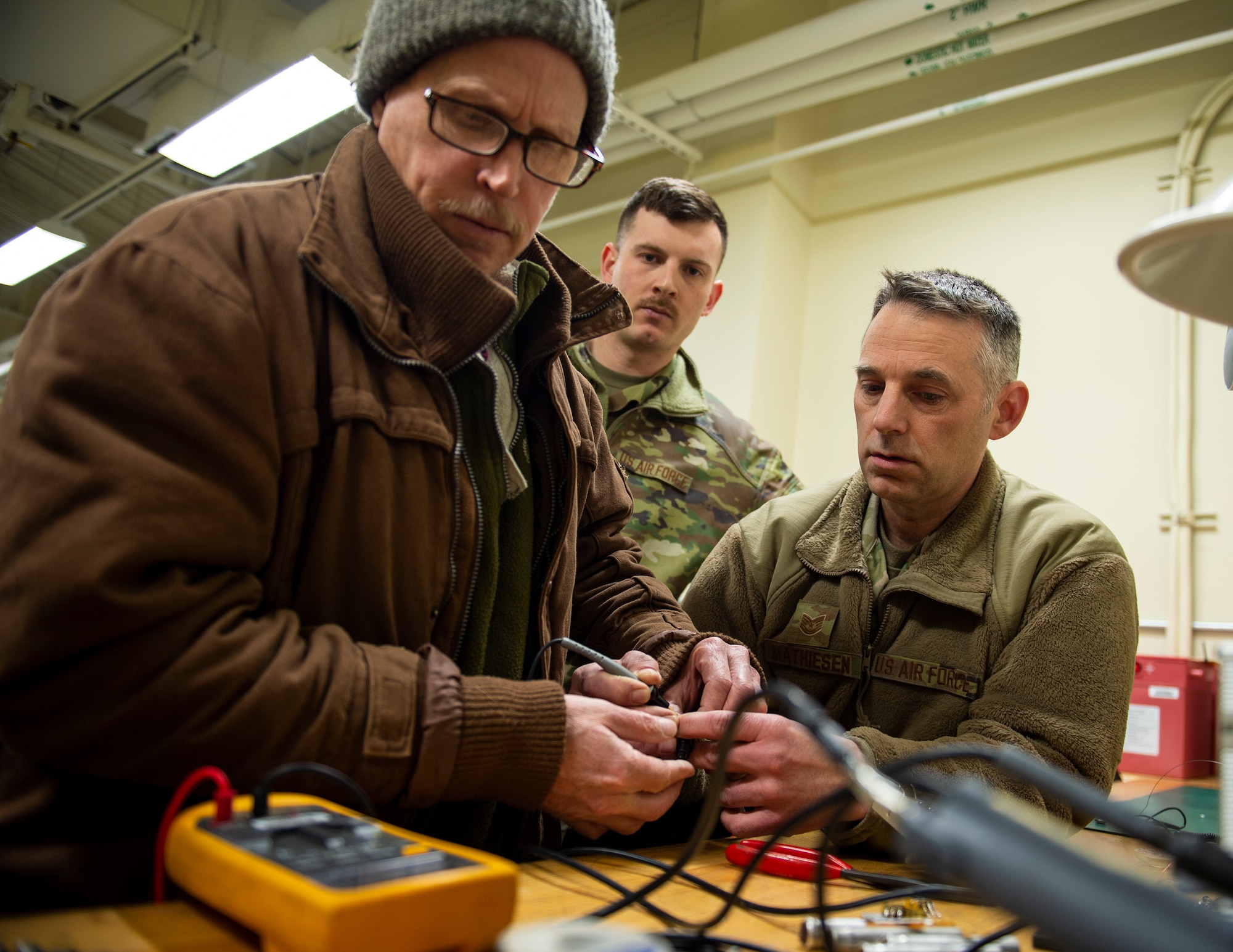 David Bethel, left, an engineer from Robbins Air Force Base, U.S. Air Force Tech. Sgt. Kyle Mayer, center, and U.S. Air Force Tech. Sgt. Scott Mathisen, right, 133rd Maintenance Squadron, test the micro unit on a trimming status panel in St. Paul, Minn., April 7, 2022.
