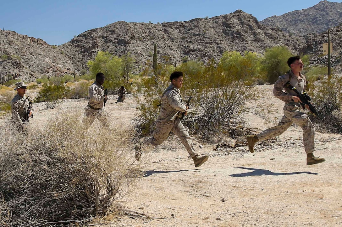 Four Marines move through a desert terrain.