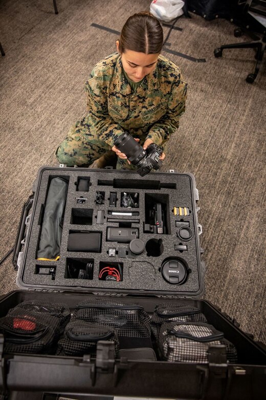 Marine inspects the gear next to an open case displaying other new equipment.