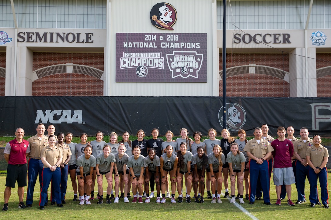 The Florida State Seminoles women's soccer team and 6th Marine Corps District staff stand inside the Seminoles soccer complex at Florida State University, Tallahassee, Florida, March 31, 2022. The 6MCD staff and the Jacksonville Officer Selection Team held leadership discussions with FSU staff and athletes and led them in events such as Battle Position, the Indoor Simulated Marksmanship Trainer, and the Marine Corps Flight Orientation Program. (U.S. Marine Corps photo by Lance Cpl. Kevin Lopez Herrera)