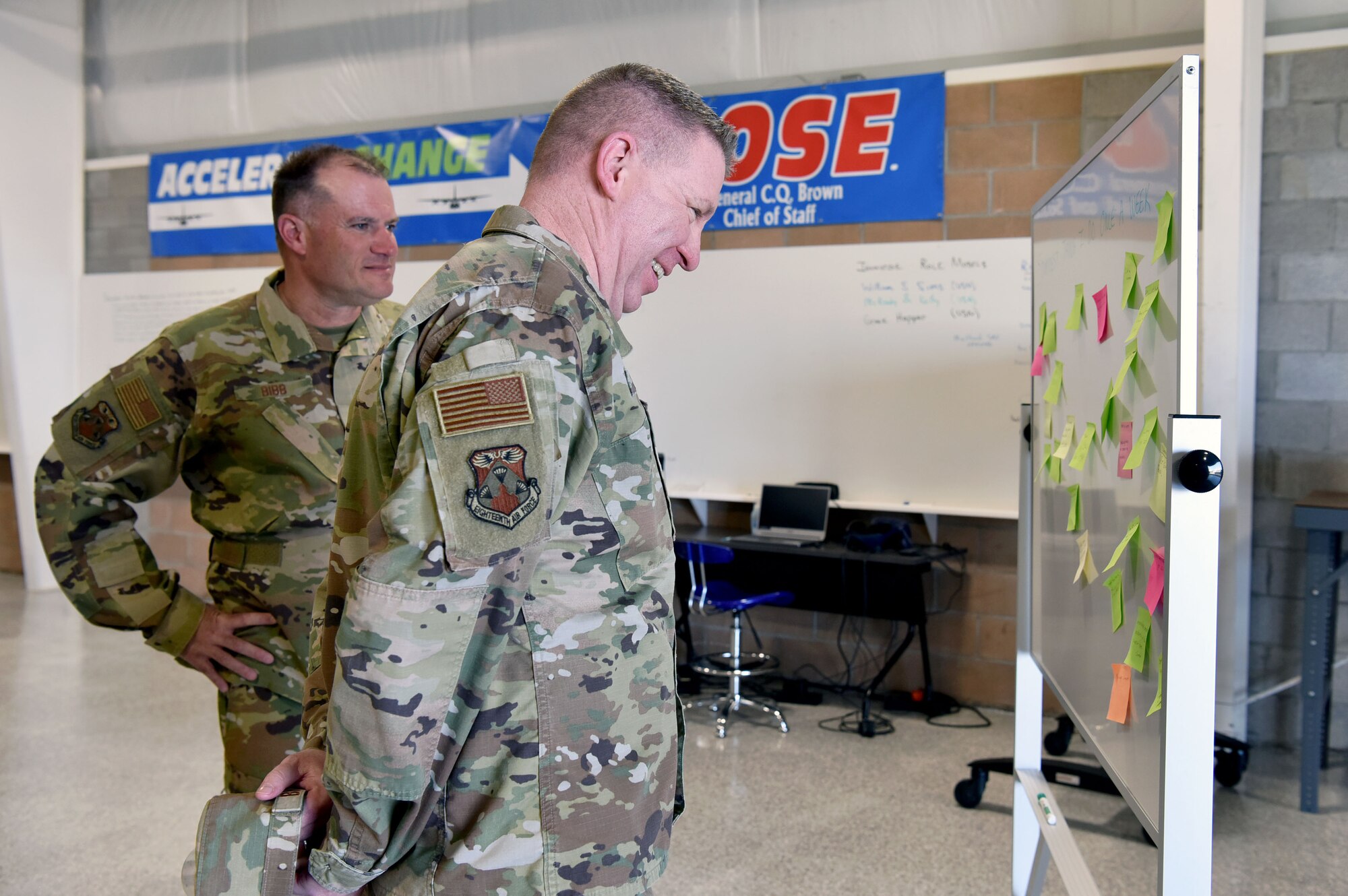 Chief Master Sgt. Chad Bickley, 18th Air Force command chief, right, and Maj. Gen. Kenneth Bibb, 18th Air Force commander, left, look over an “idea board” located within the HERKWERX innovation lab