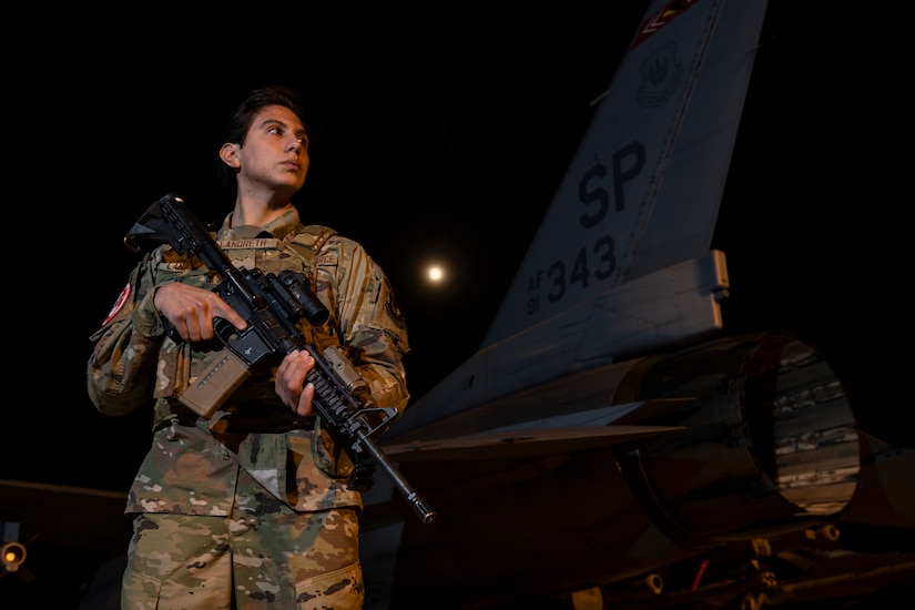 An airman stands guard over an aircraft.