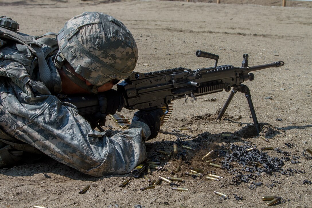 A soldier lies on the ground with a rifle in a firing position.