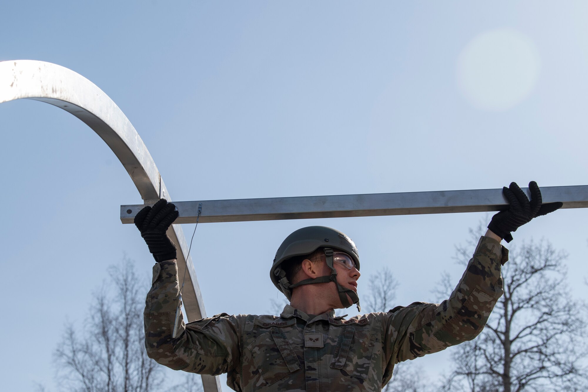A photo of a man lifting a beam in front of a blue sky