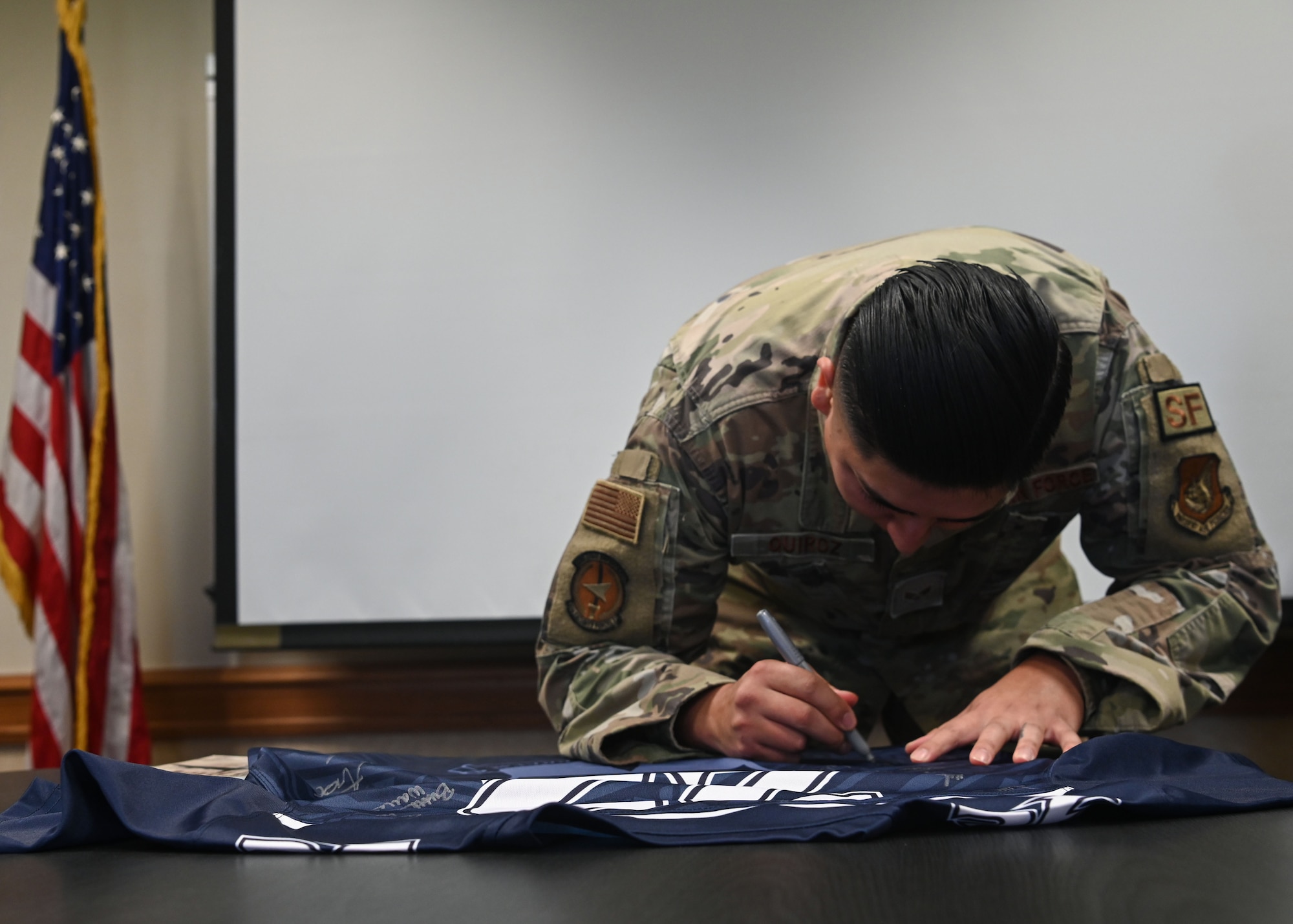 U.S. Air Force Senior Airman Alex Quiroz Jr., a Base Defense Operations Center Controller with the 36th Security Force Squadron, signs the Linebacker jersey after being awarded the Linebacker of the Week award at Andersen Air Force Base, Guam, April 13, 2022.