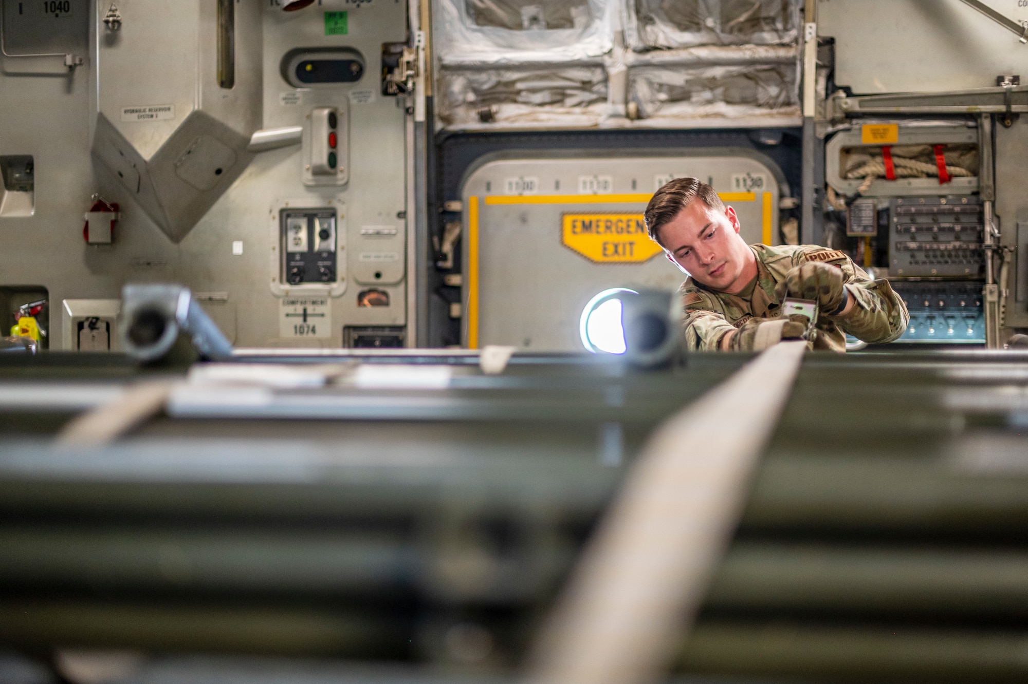 A man straps in a large military vehicle that is used to load pallets on to large military aircraft, in side of a C-17 Globemaster III, a large Air Force aircraft.