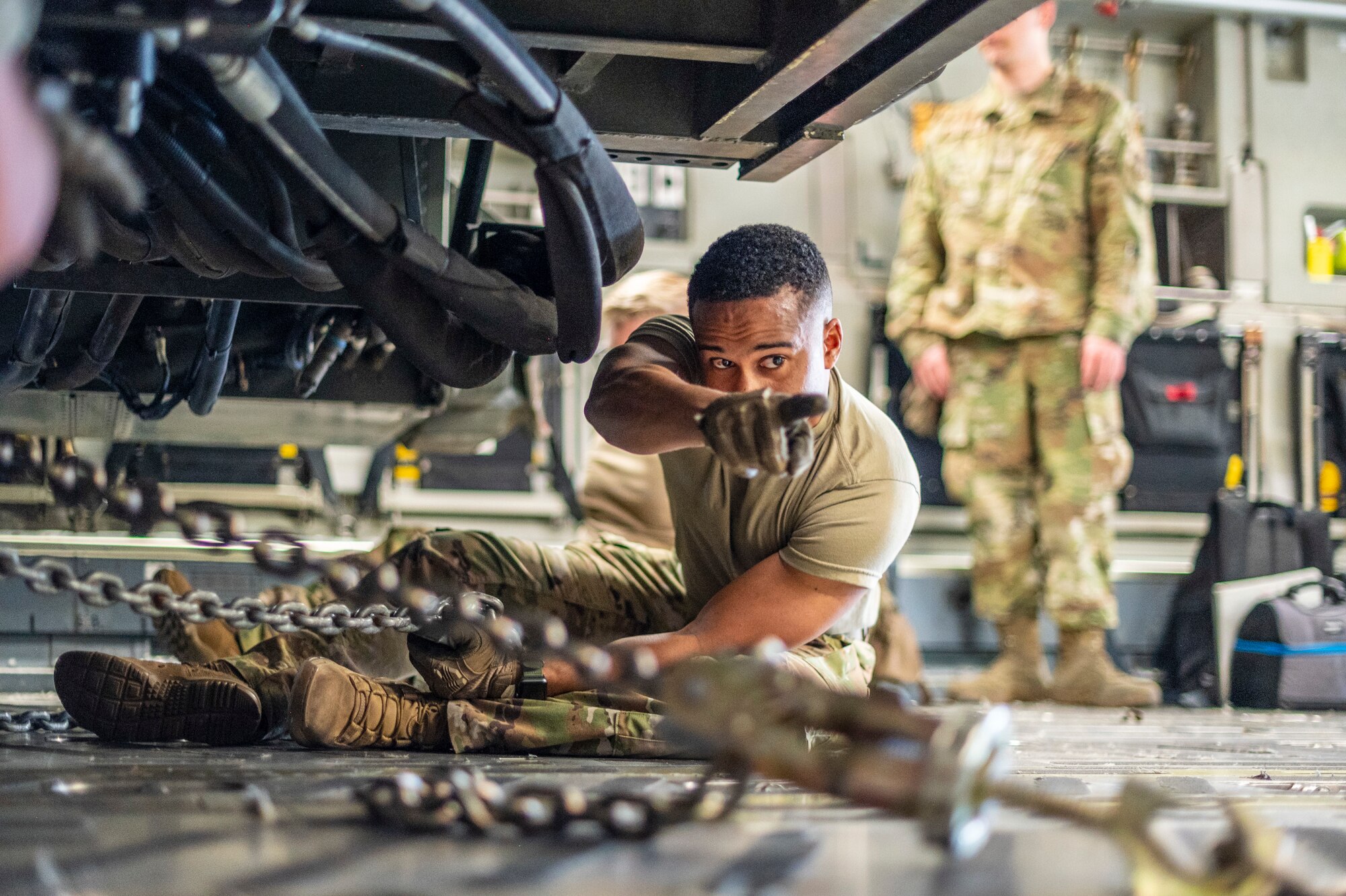 A man straps in a large military vehicle that is used to load pallets on to large military aircraft, in side of a C-17 Globemaster III, a large Air Force aircraft.