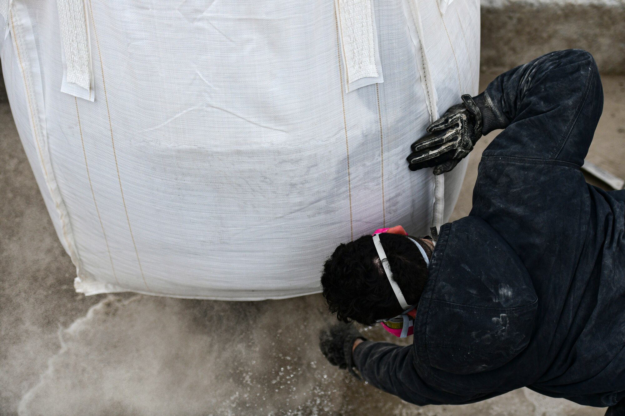 An Airman cuts a bag of concrete.
