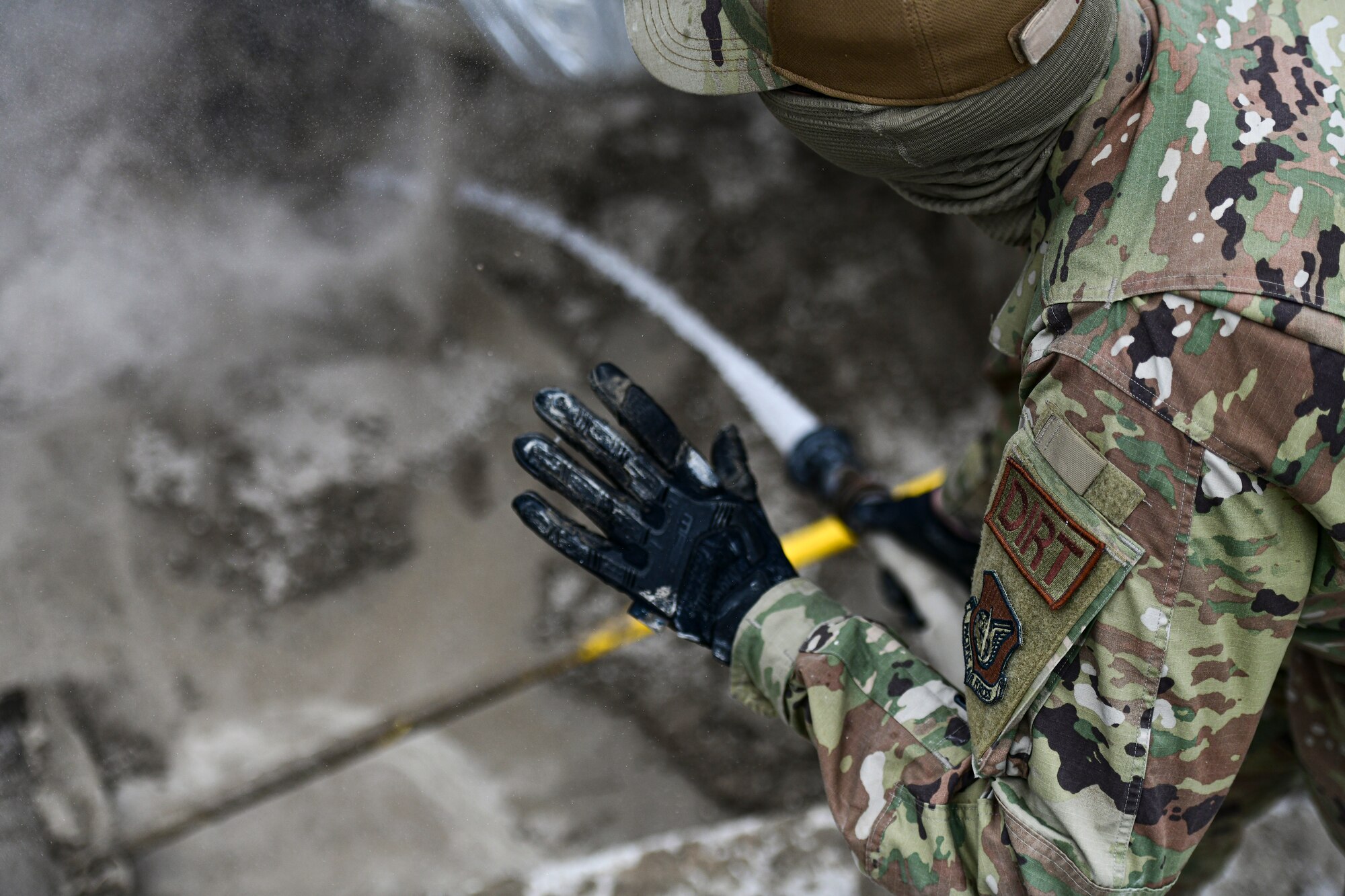 An Airman sprays water on concrete.