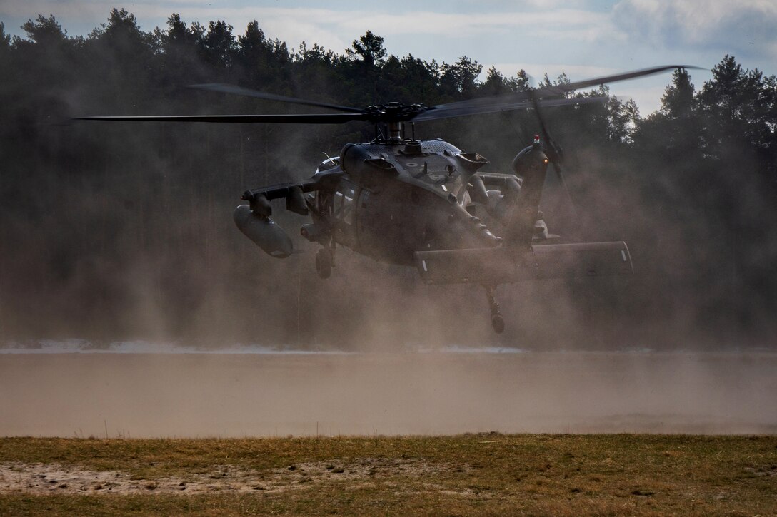 Just above the ground, a helicopter kicks up dust with its rotors.