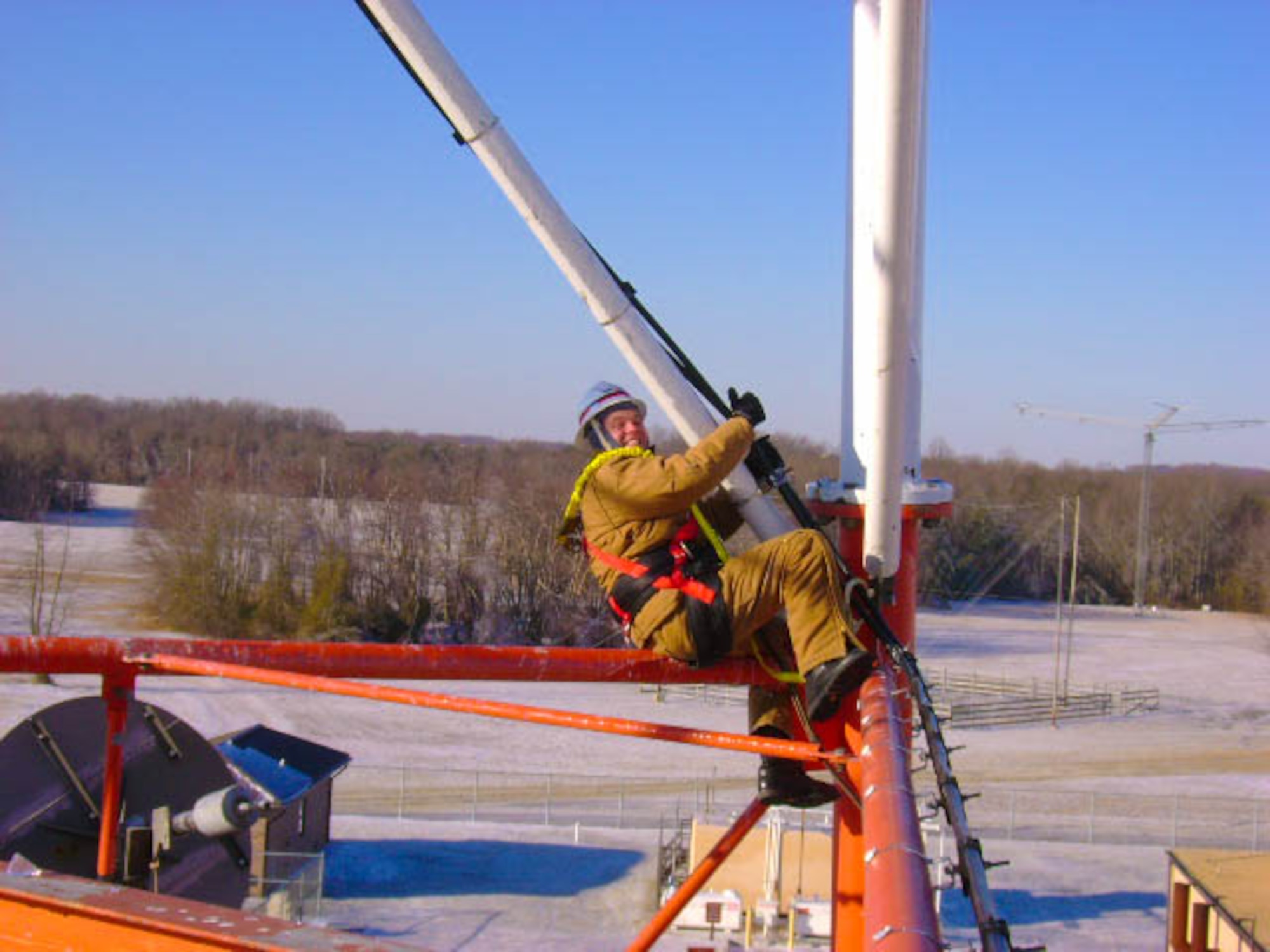 Holcomb climbing a pole while fixing an antenna