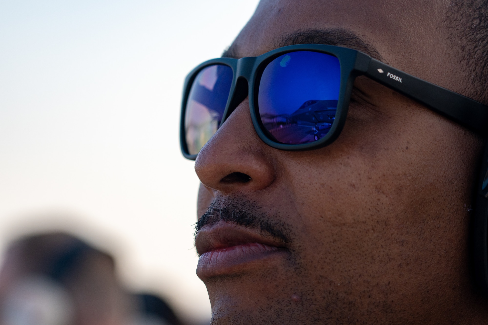 Photo of a man wearing sunglasses looking at a fighter jet