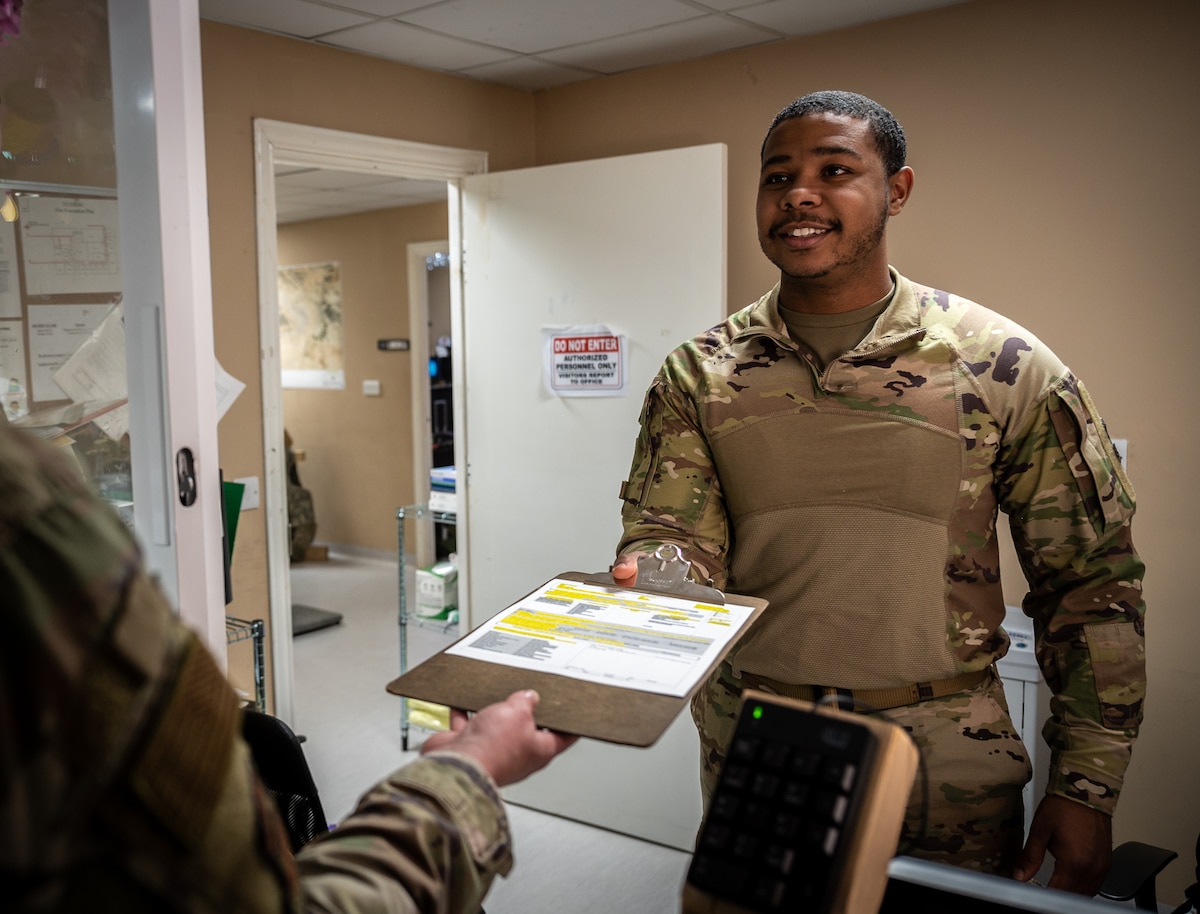 U.S. Air Force Senior Airman Tommy D. Jones, 332d Expeditionary Medical Group laboratory technician, hands a new patient intake questionnaire to a 332d Air Expeditionary Wing Airman at an undisclosed location in Southwest Asia, April 6, 2022. Jones is the 332d EMDG’s sole laboratory technician and is one of many multi-capable Airmen within the 332d EMDG supporting daily operations. (U.S. Air Force photo by Master Sgt. Christopher Parr)