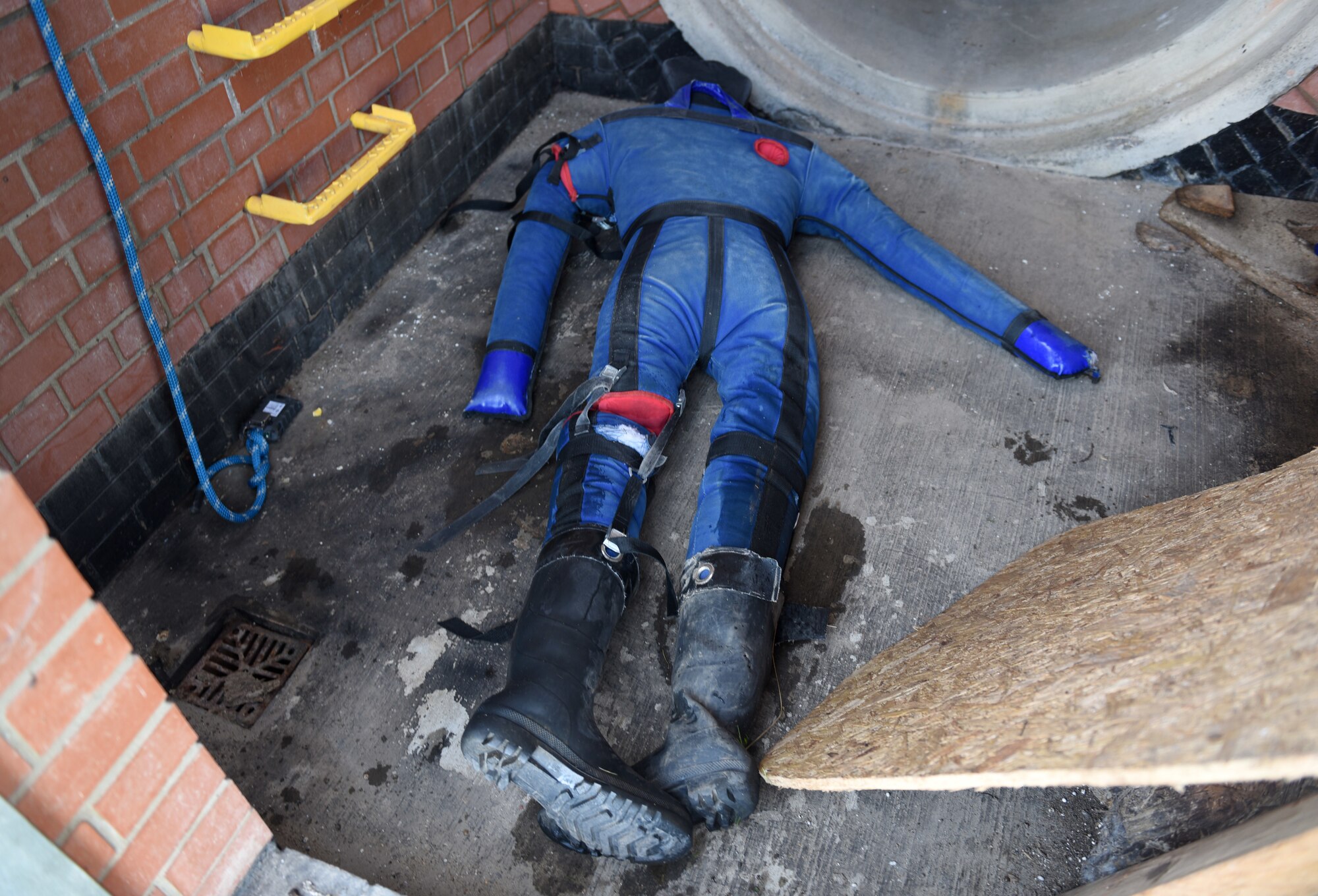 A simulated casualty lays at the bottom of a facility as part of confined space training for 100th Civil Engineer Squadron firefighters at Royal Air Force Mildenhall, England, April 14, 2022. The training scenario was that a teenager (simulated by a mannequin) was playing and climbing down inside the building to check it out, when he fell and injured himself. In the scenario, a firefighter climbed down to rescue the casualty but slipped on a broken step, sustained injuries, and also had to be rescued. (U.S. Air Force photo by Karen Abeyasekere)
