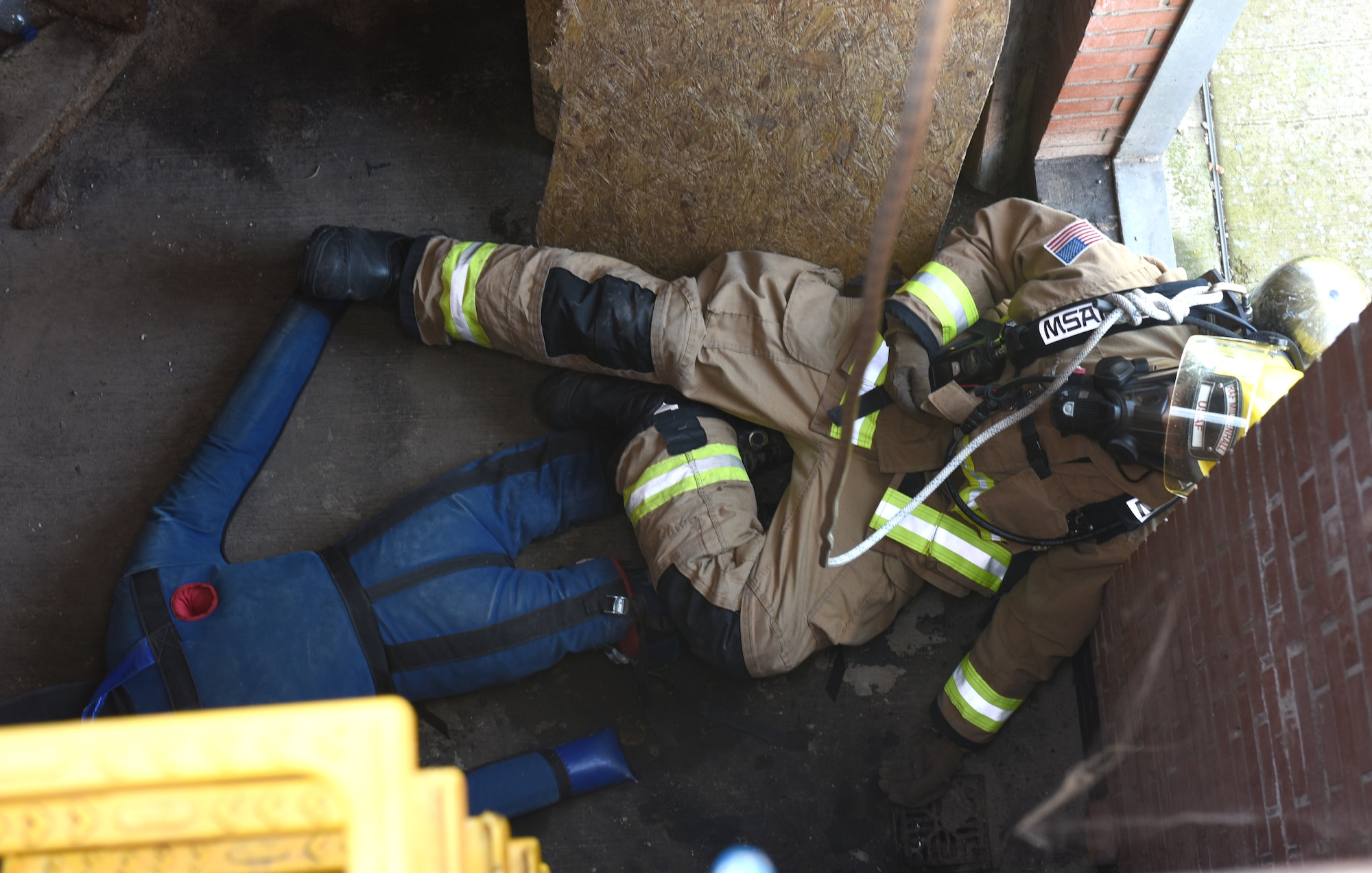 U.S. Air Force Airman 1st Class Robert Cataldo, 100th Civil Engineer Squadron Fire Department firefighter, simulates being a second casualty during a confined space training exercise at Royal Air Force Mildenhall, England, April 14, 2022. The scenario involved a teenager (simulated by a mannequin) who fell and was injured after climbing down into a facility. While climbing down to rescue the victim, Cataldo simulated falling after slipping on a broken step, so other firefighters from his team had to complete the rescue. This type of training is vital to the first responders to provide them with the necessary skills to extricate wounded or trapped personnel, including high-angle litter and stretcher evacuation. (U.S. Air Force photo by Karen Abeyasekere)