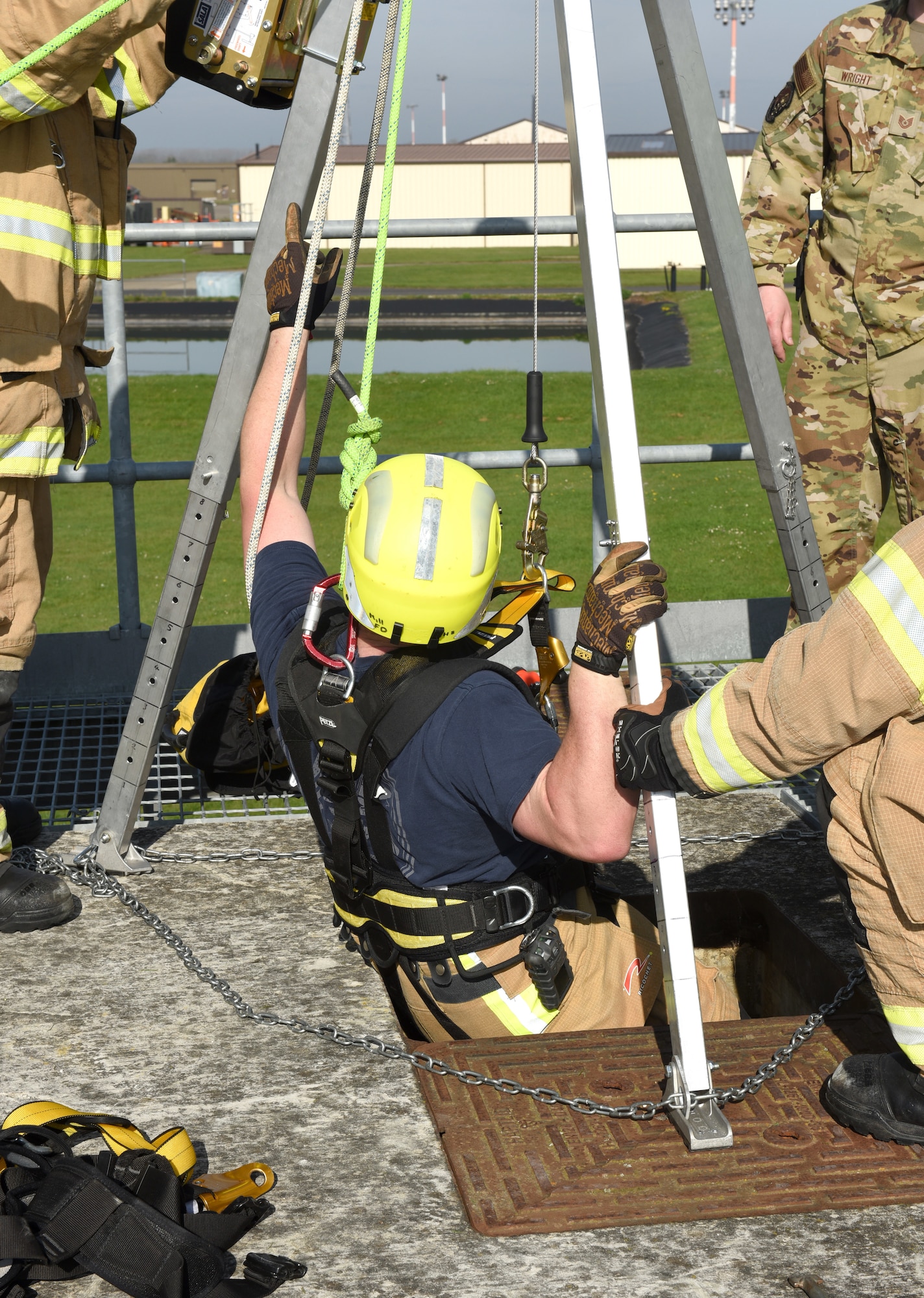 Firefighter Eddie Brant, 100th Civil Engineer Squadron Fire Department, rappels down into a confined space as other firefighters ensure he is securely attached and safe, during a training exercise at Royal Air Force Mildenhall, England, April 14, 2022. The scenario involved a teenager (simulated by a mannequin) who fell and was injured after climbing down into a facility. While climbing down to rescue the victim, another firefighter simulated also falling after slipping on a broken step, so Brant had to complete the rescue. (U.S. Air Force photo by Karen Abeyasekere)