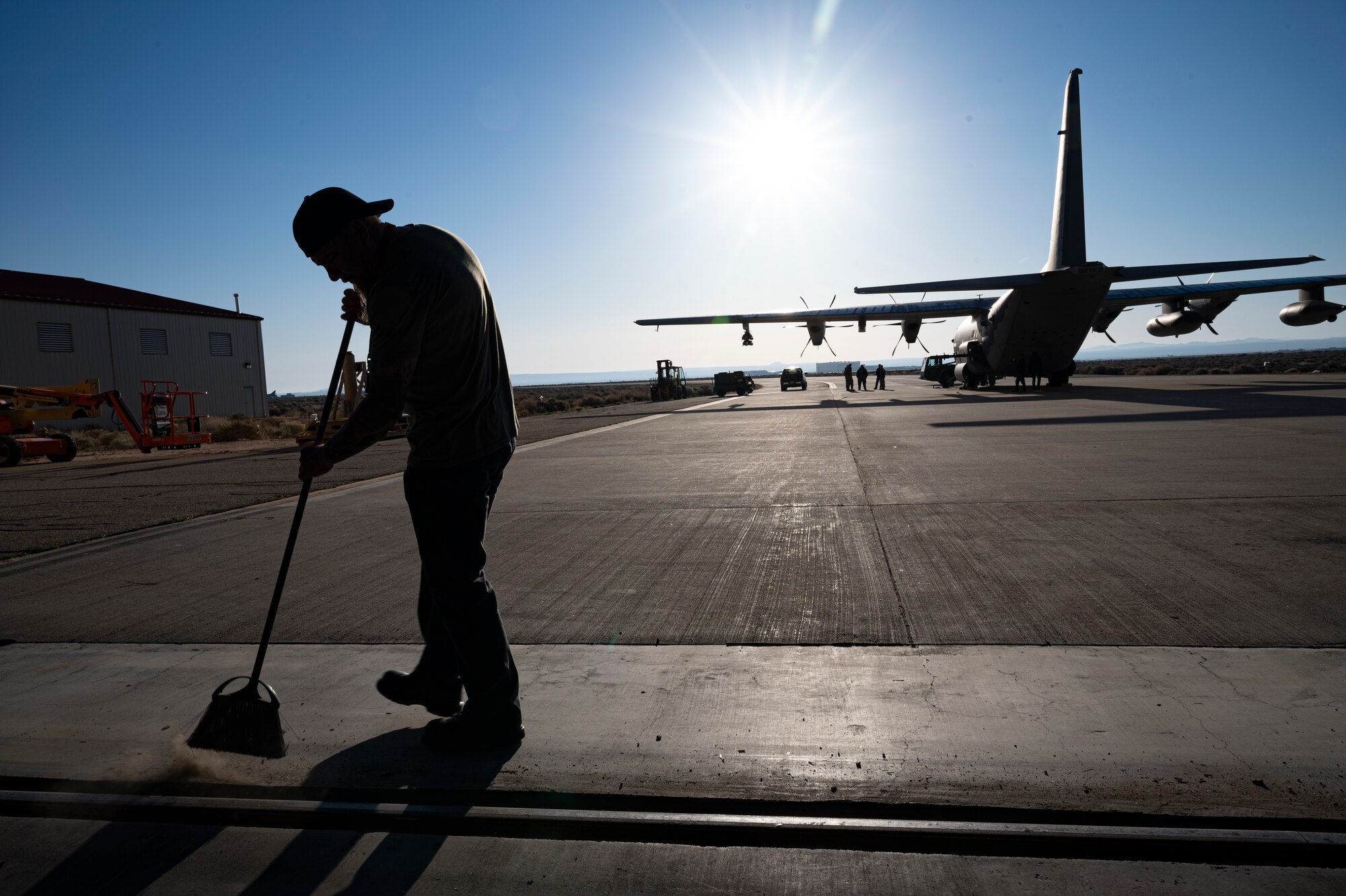 A crew member sweeps the ramp before a C-130 rolls into the BAF.